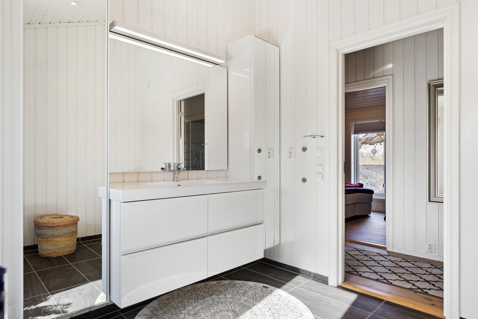 Badet er utstyrt med en praktisk servantinnredning, skap, speil med overlys, dusjkabinett og vegghengt toalett. Galleribilde