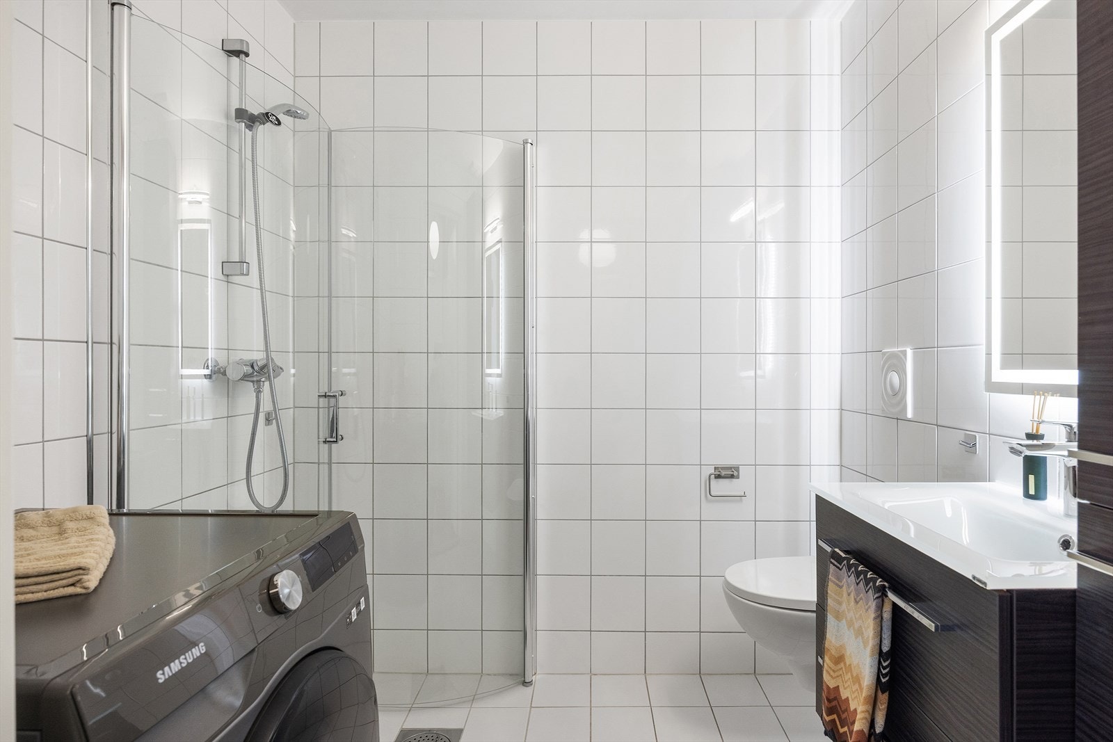 Pent flislagt baderom med gulvvarme og opplegg for vaskemaskin. Galleribilde