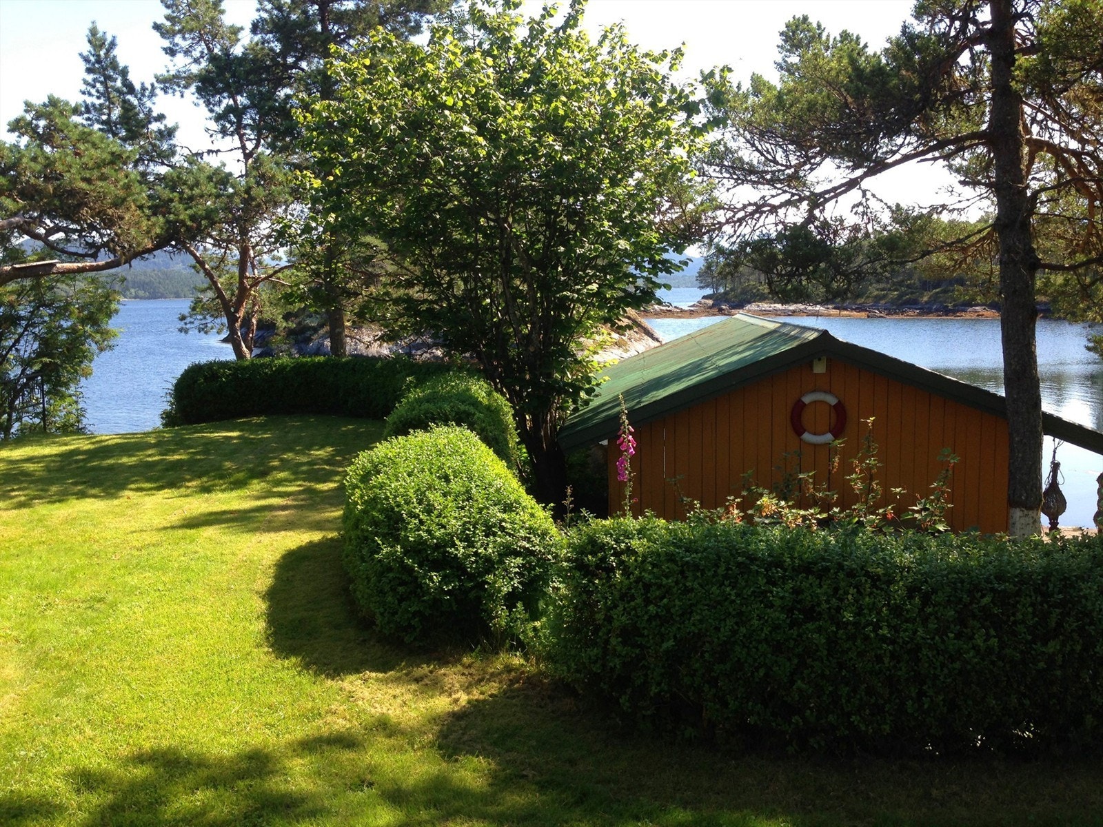 Tomten er pent opparbeidet med plen og beplantning, samt fine muligheter for bading og lek Galleribilde