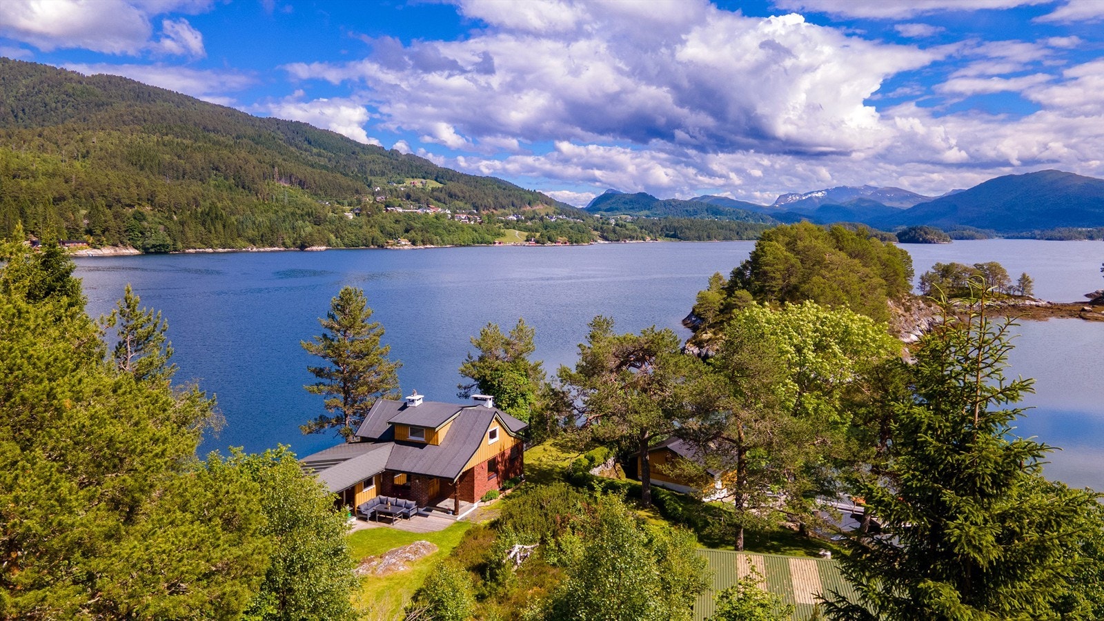 Dronebilde av eiendommen sett fra vest mot øst med boligfeltet i Grindvika på Skodje i bakgrunnen Galleribilde
