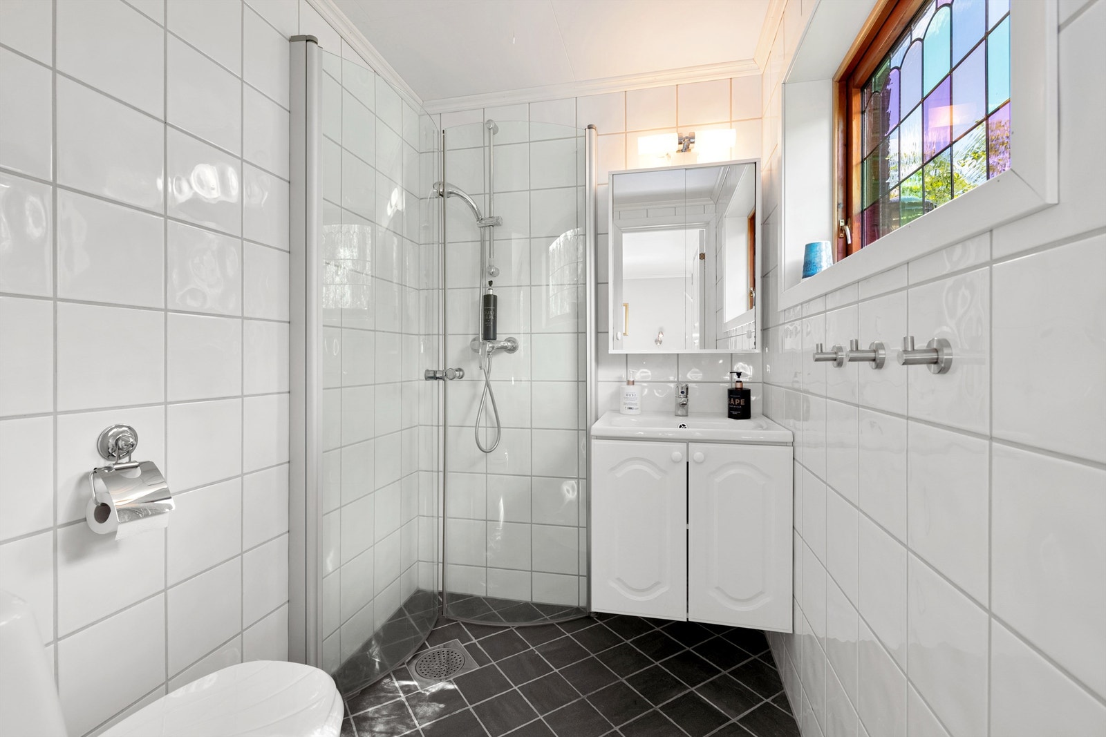 Flislagt bad fra 2015 med wc, innredning med servant, speil med overlys og dusjhjørne med foldbare glassvegger Galleribilde