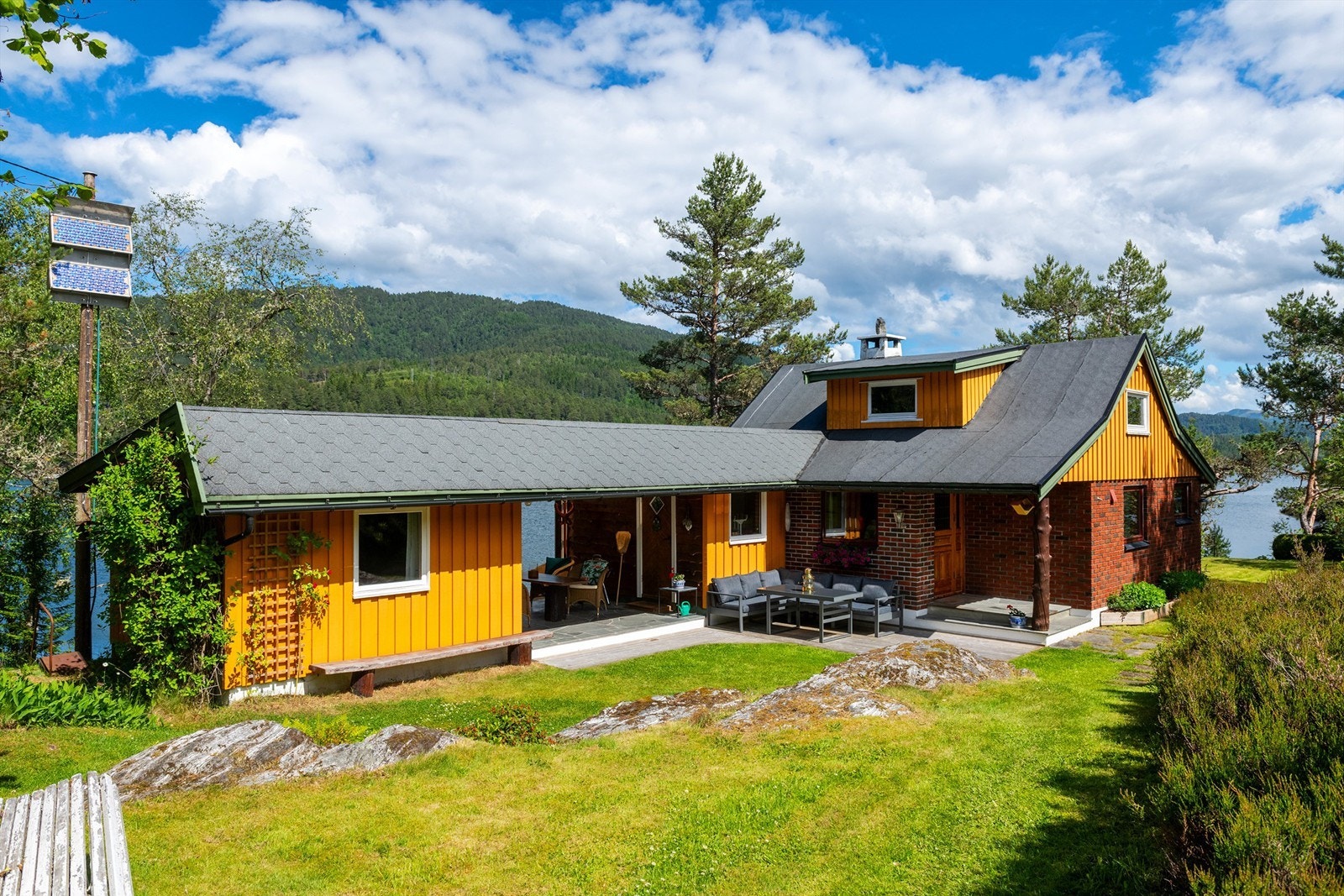 Fasade med markterrasse og hage og overbygget utestue Galleribilde