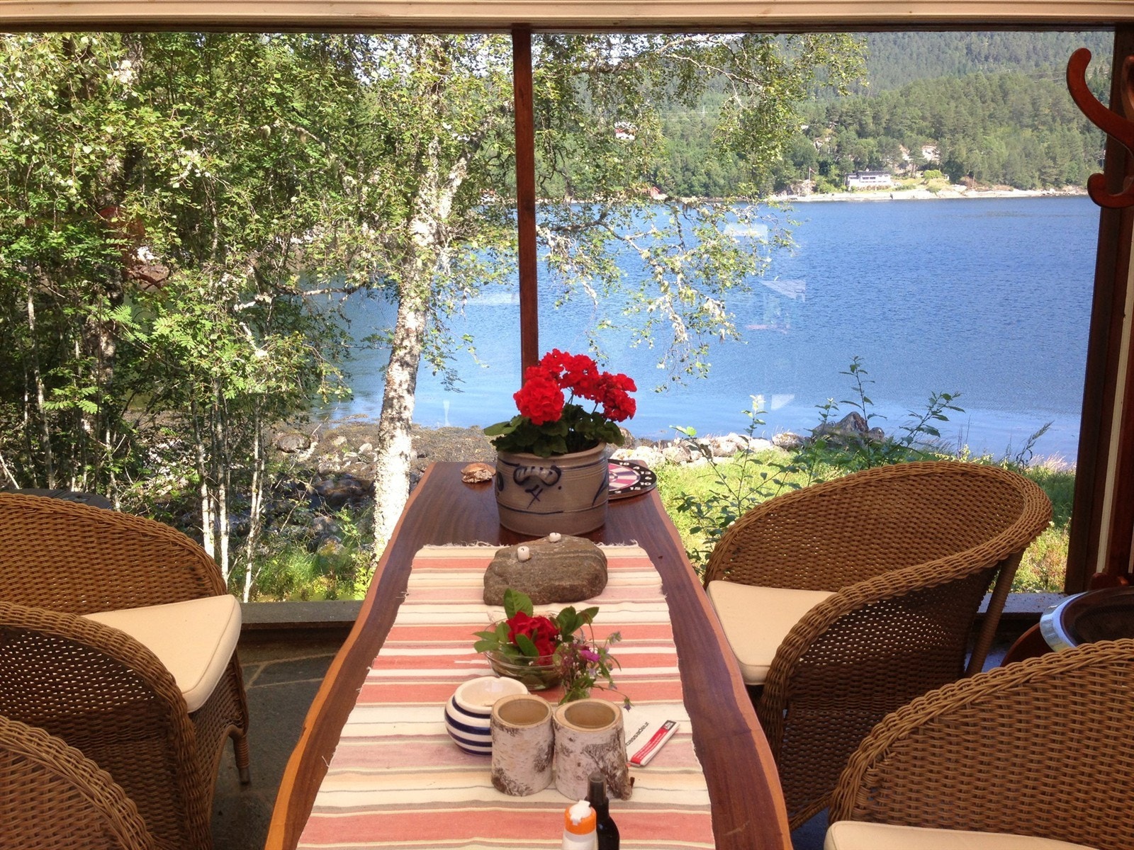 Det er laget til flott overbygget utestue/uteområde under tak på tilbygget del med flott utsikt mot sjøen Galleribilde