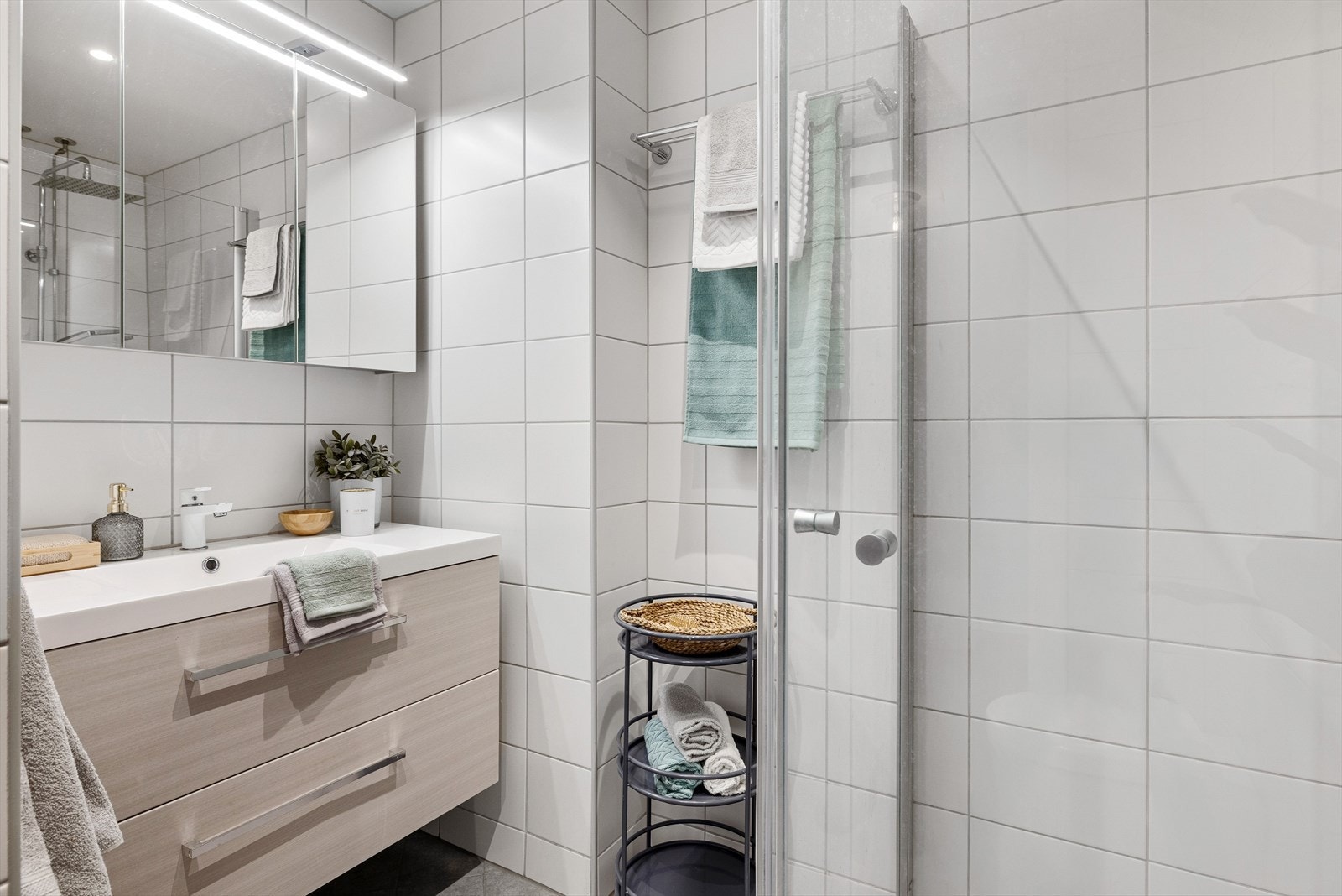 Leiligheten har et lyst og pent baderom som ble pusset opp i regi av aksjelaget i 2019. Baderommet har grå fliser på gulv med gulvvarme, hvite fliser på veggene, downlights i himlingen og mekanisk avtrekk. Galleribilde