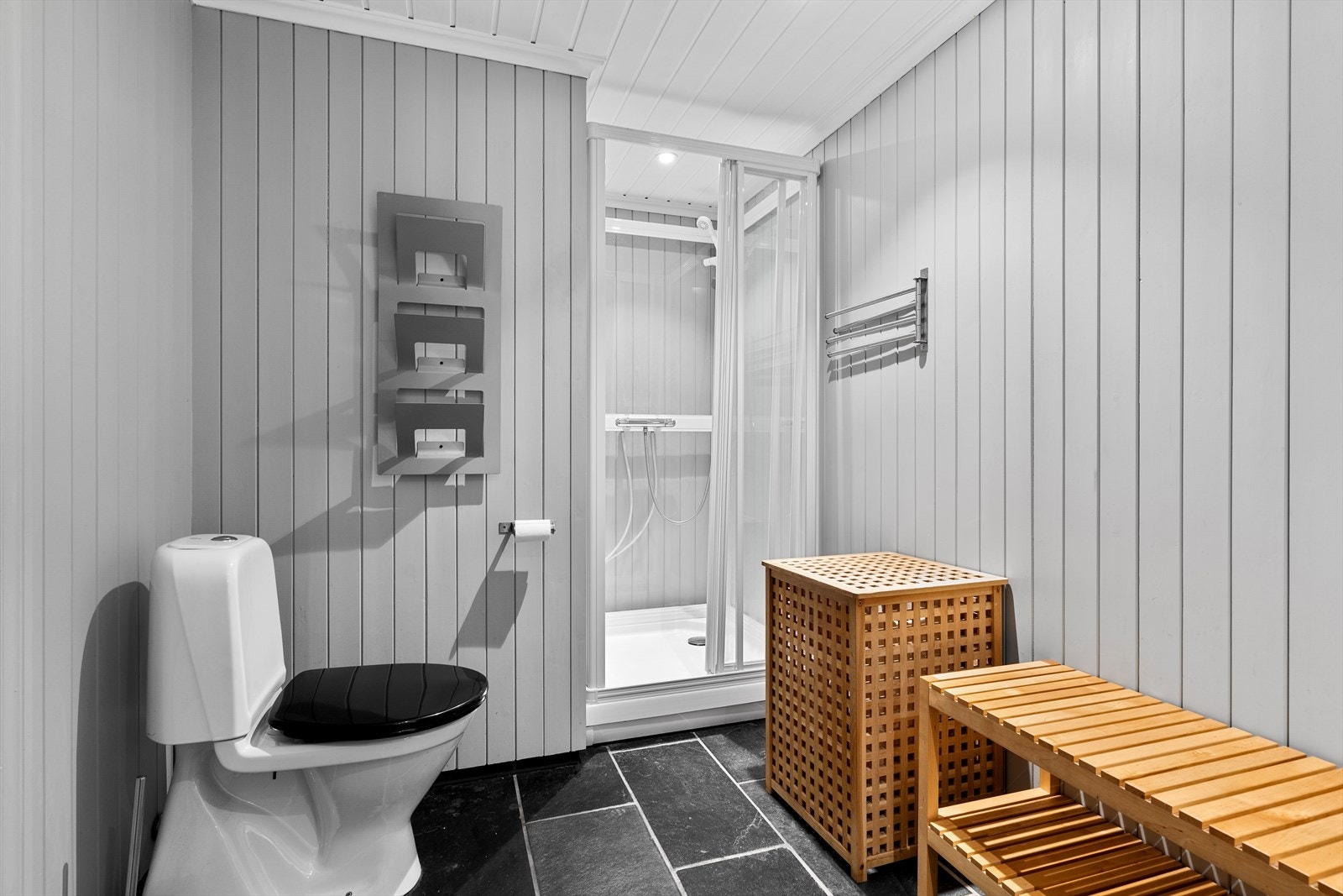 Badet har skiferfliser på gulvet med varmekabler, samt at det inneholder et toalett, dusjkabinett, samt vask/innredning med speil over. Rommet er ikke godkjent for varig opphold. Galleribilde