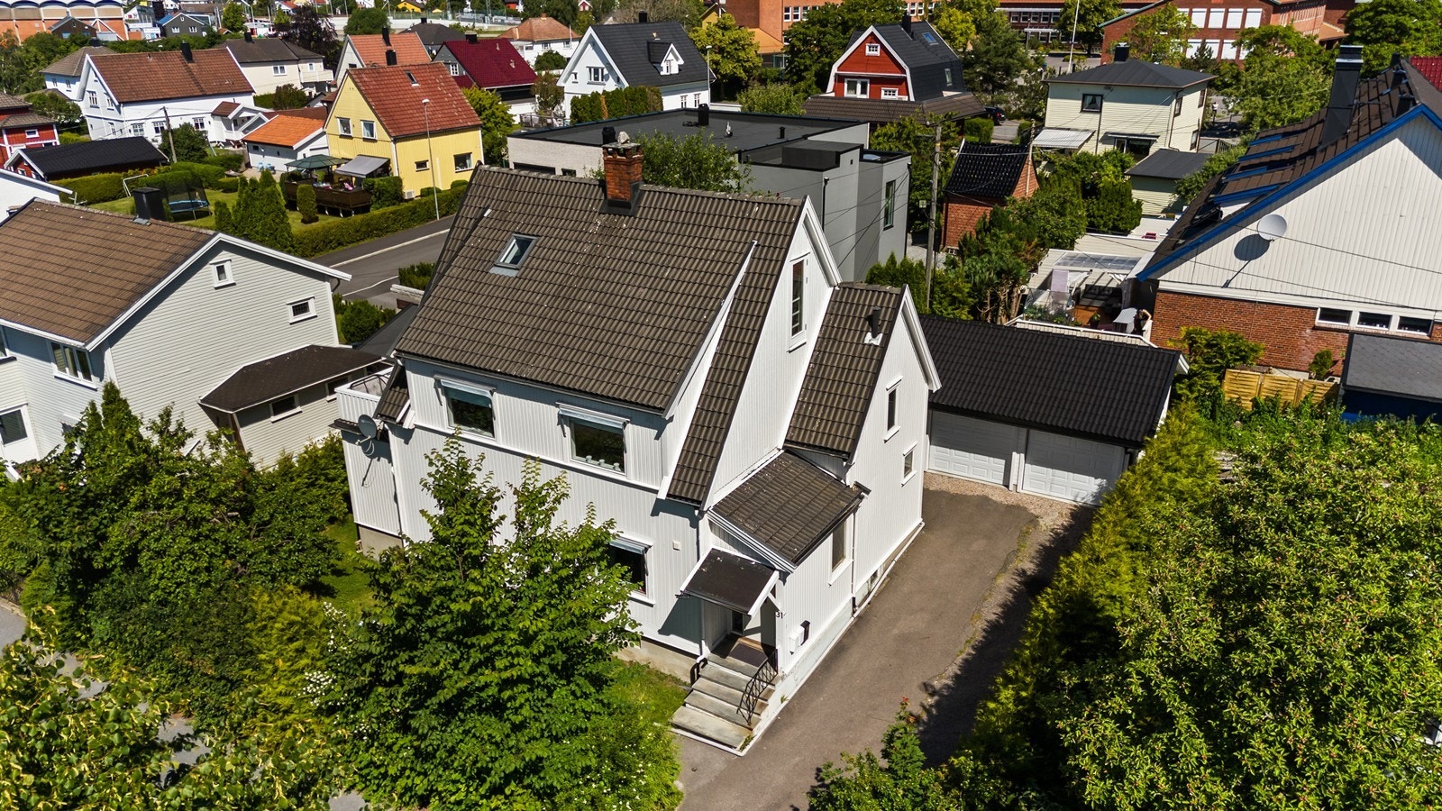 Fasade og området sett i fra luften. Tomten er opparbeidet med grøntarealer og innkjørsel Galleribilde