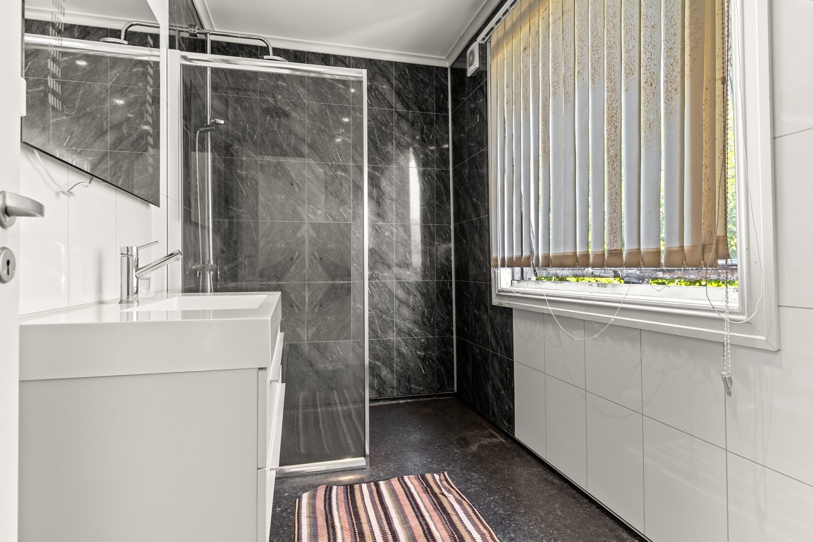 Baderommet i 2. etasje har belegg på gulvet og våtromsplater på veggene. Det er utstyrt med moderne servantinnredning og dusjnisje Galleribilde