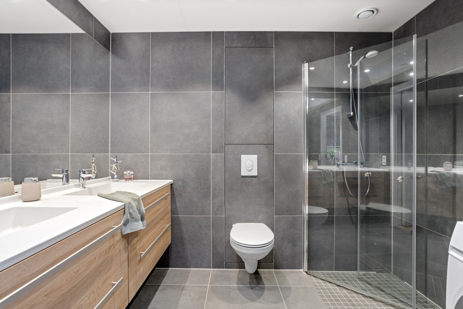 Elegante storformatfliser i bad/wc | dobbelvask | dusjvegger i glass | vegghengt wc | downlights | heldekkende speil Galleribilde