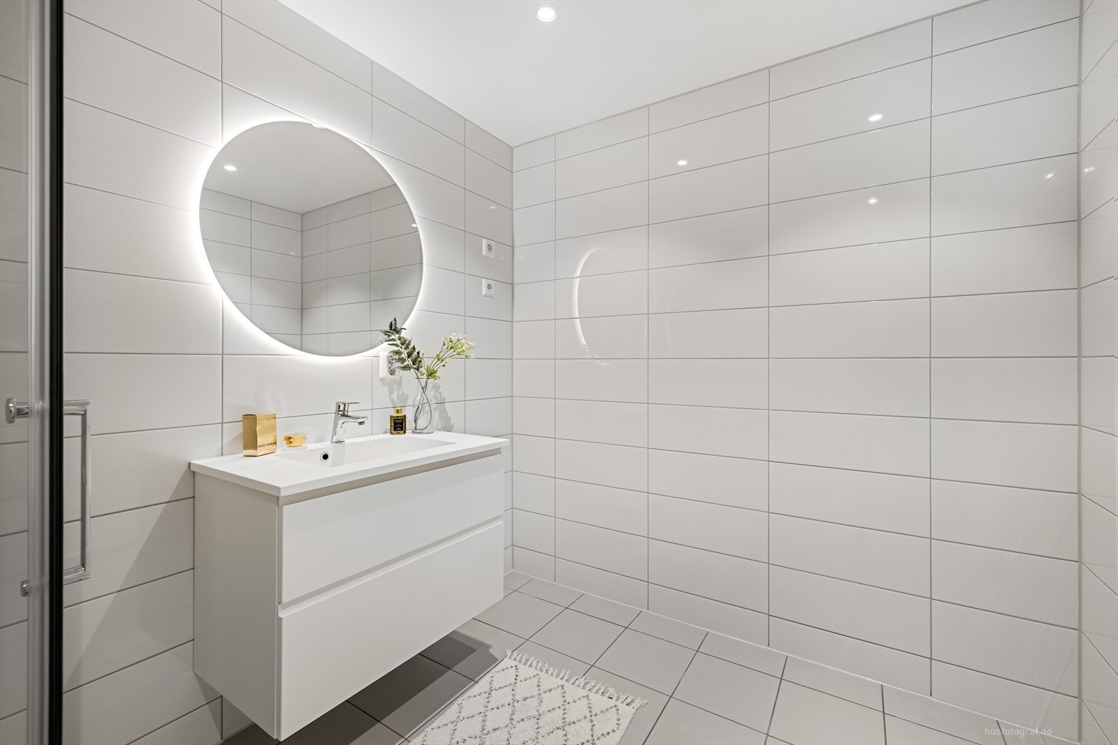 Stilrent bad innredet med lyse, moderne fliser, mosaikkfliser i dusjsonen og varmekabler i gulv. Galleribilde
