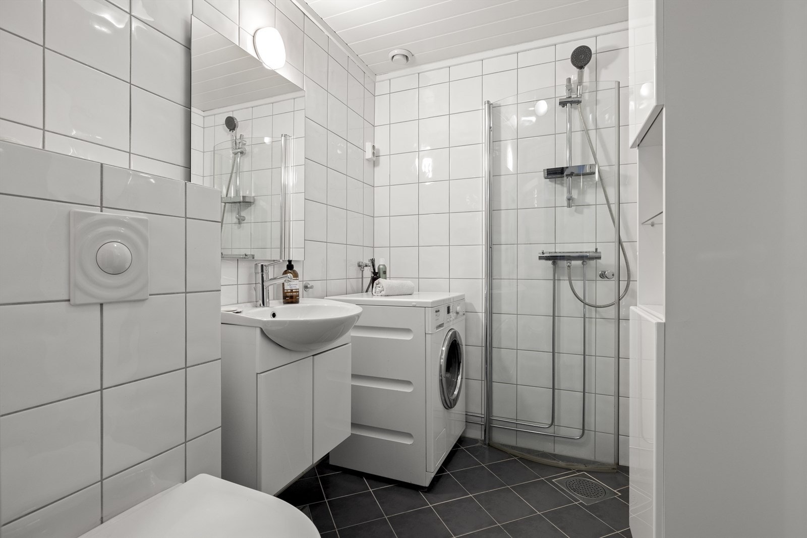 Badet er pent flislaget, og det er montert servant, speil, dusj, toalett og opplegg for vaskemaskin. Galleribilde