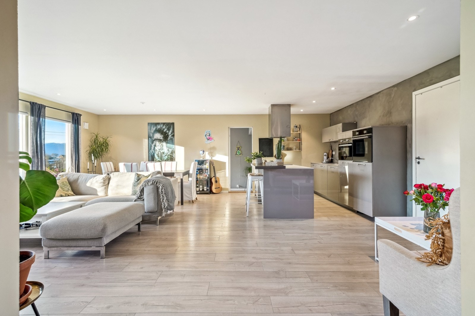 Romslig åpen stue/kjøkken-løsning med store vindusflater mot syd. Galleribilde