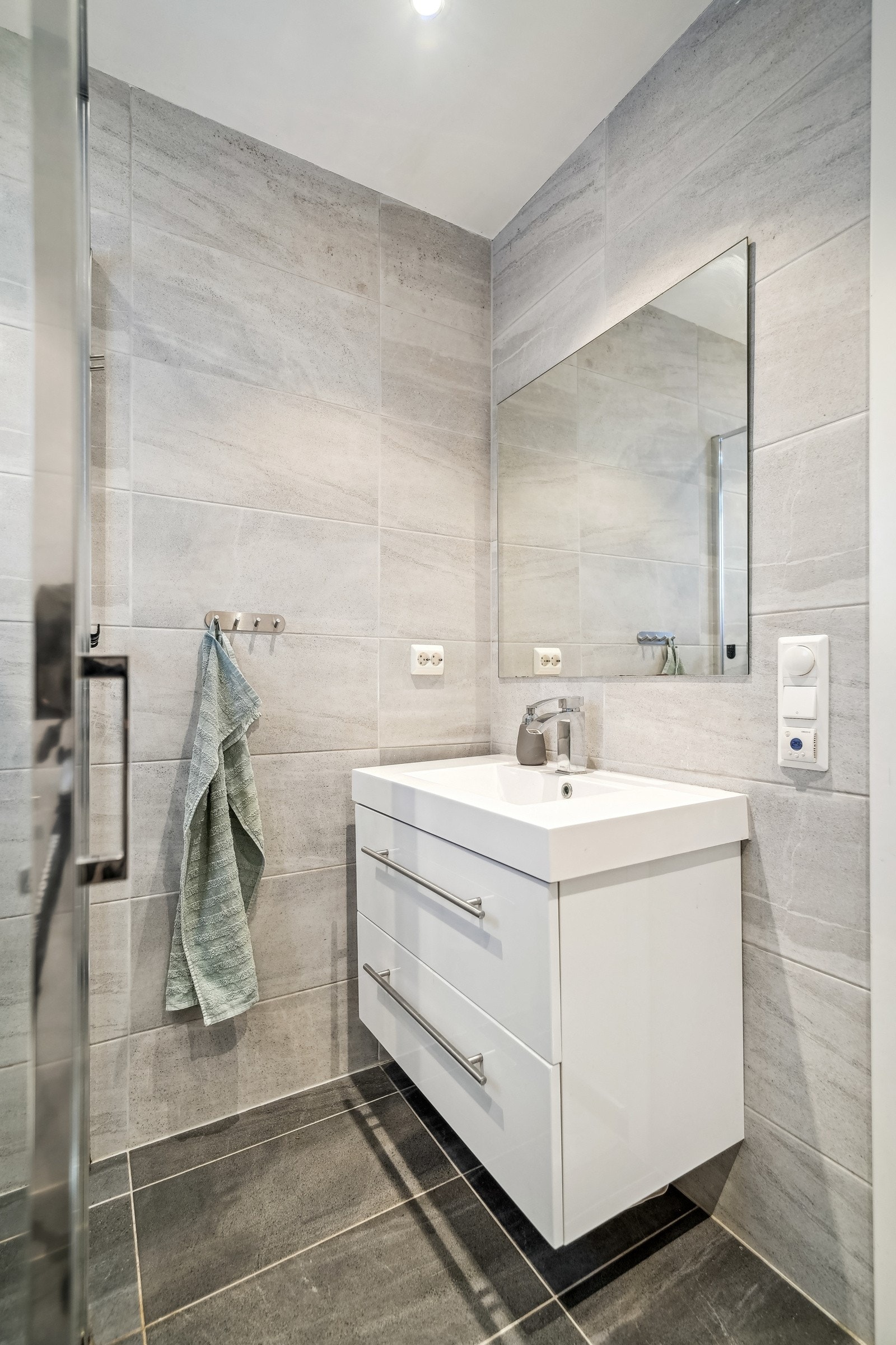 Innredet med dusjhjørne, vegghengt toalett, servantinnredning og speil. Galleribilde