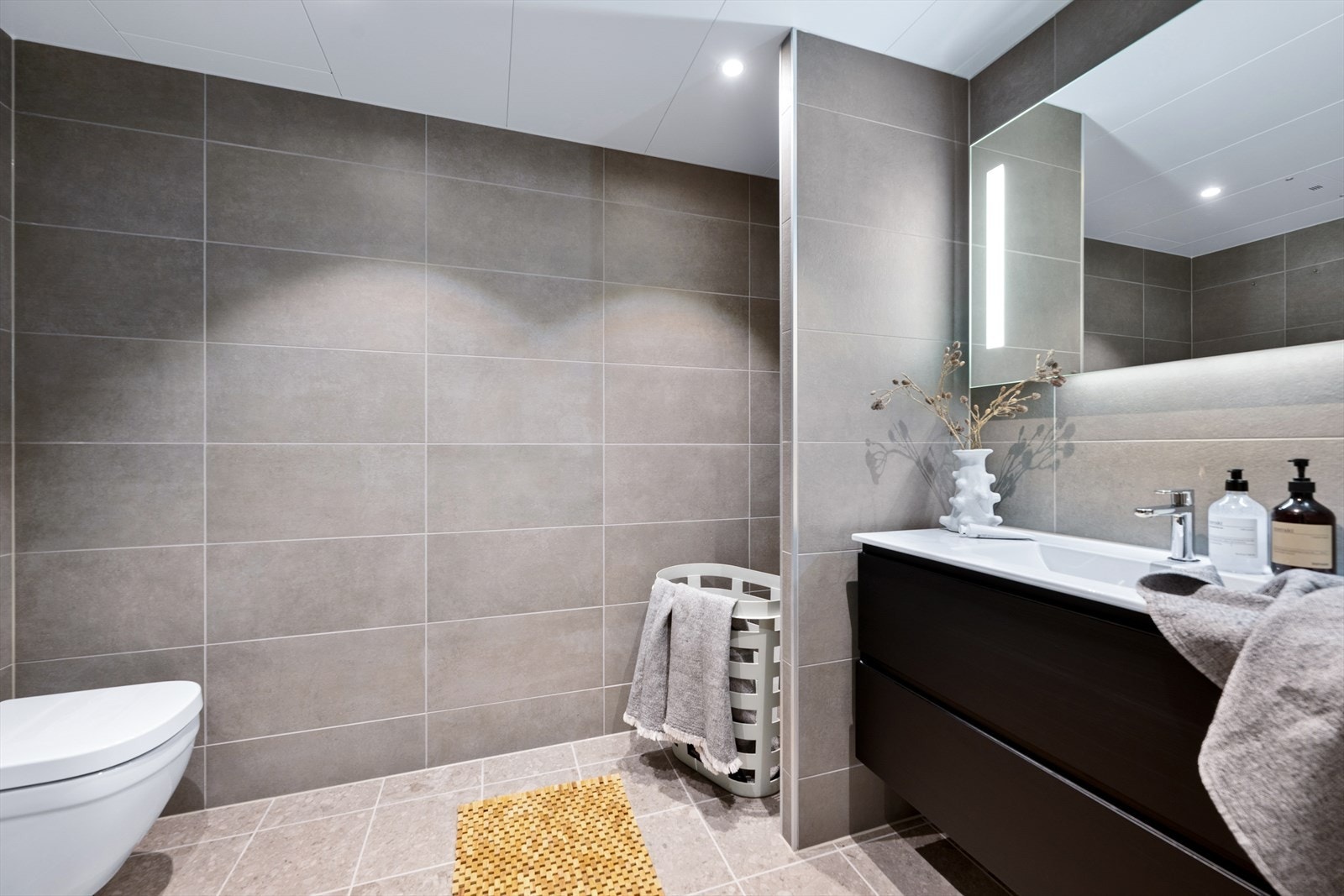 Leiligheten har et delikat flislagt baderom med downlights i himling og varme i gulv - Badet er innredet med et servantskap på 120 cm i sort eik med struktur med nedfelt servant og blandebatteri fra Tapwell Galleribilde