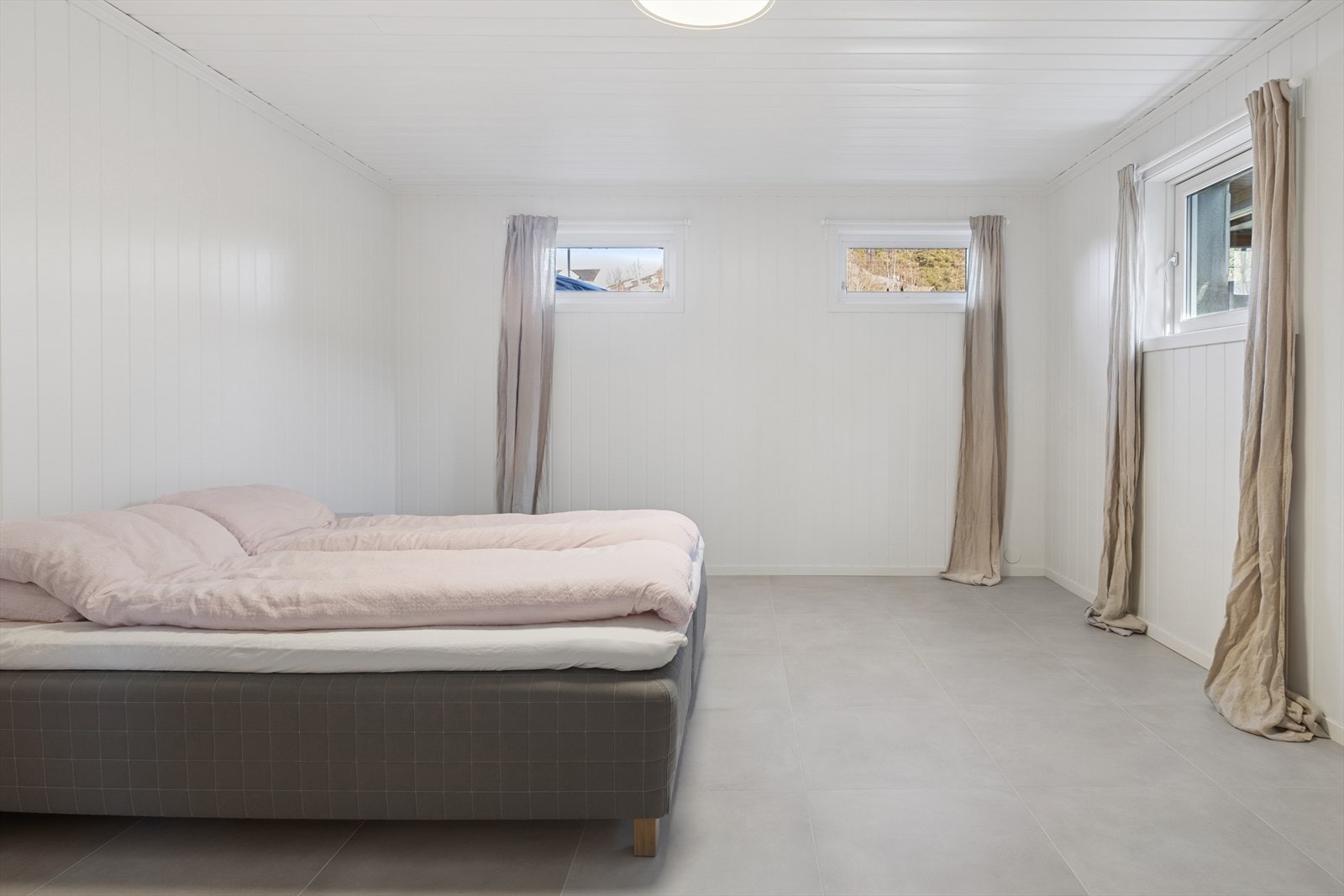 Lyst og innbydende soverom i kjeller. Fliser og varmekabler. Galleribilde