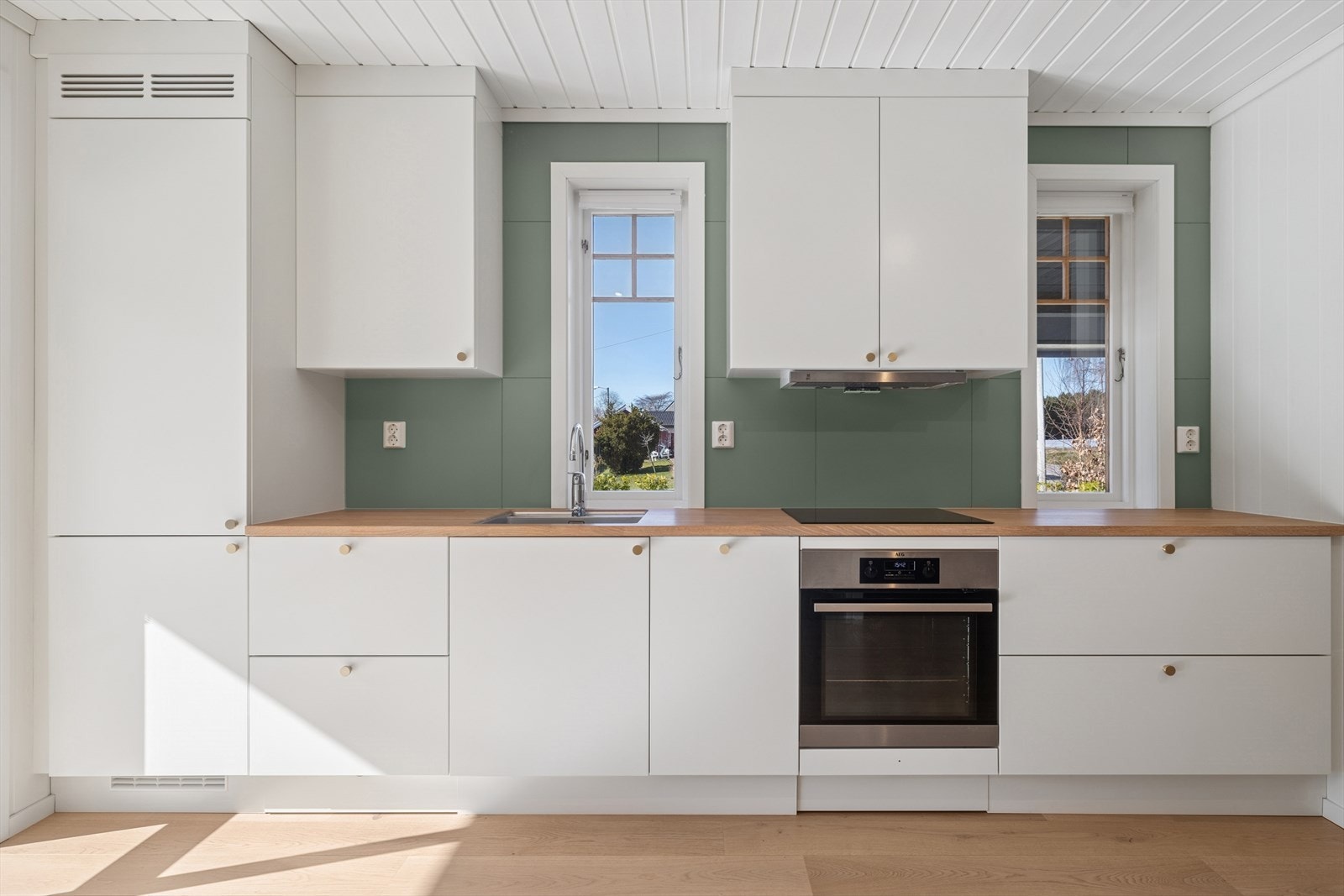 Moderne kjøkkeninnredning med integrerte hvitevarer fra 2021. Benkeplate i heltre eik med underlimt vask. Galleribilde