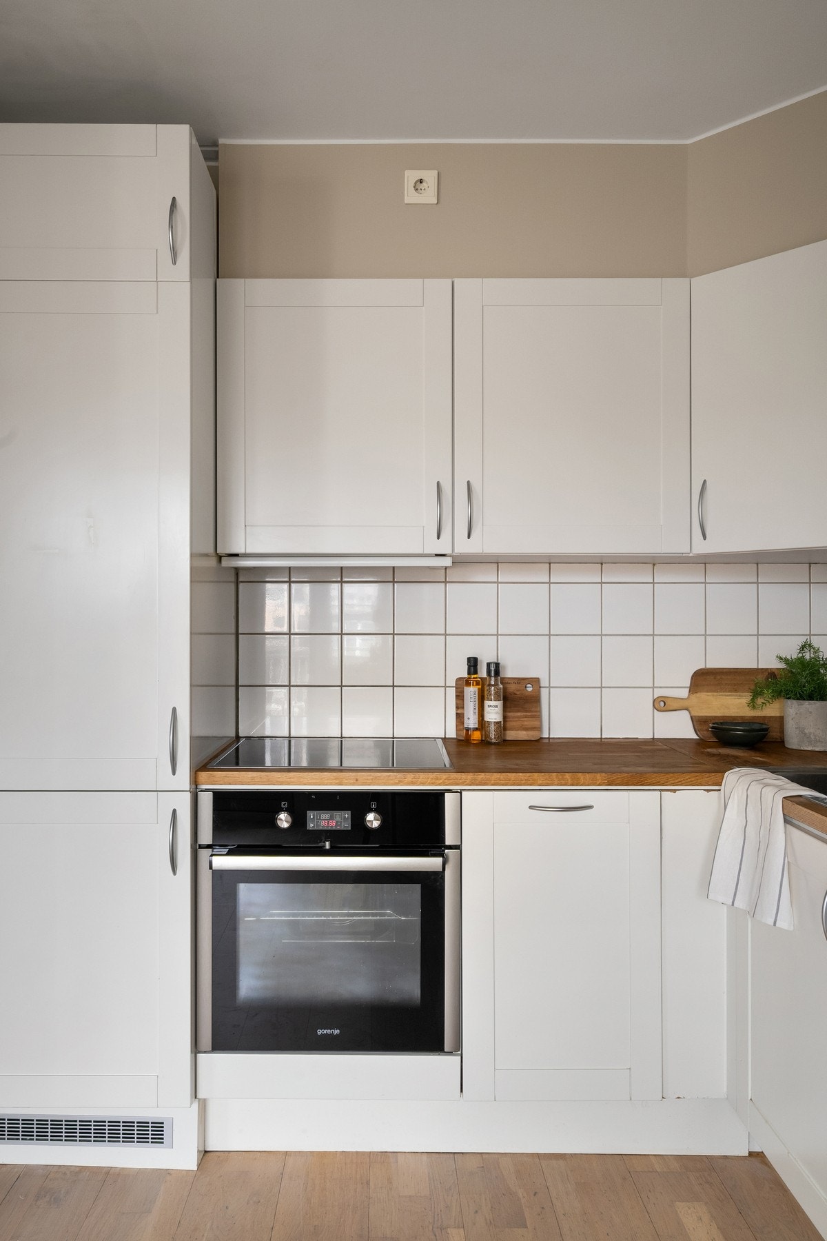 Kjøkkeninnredning med malte fronter, eik benkeplater, kjøl/fryseskap, stekeovn og keramisk platetopp Galleribilde