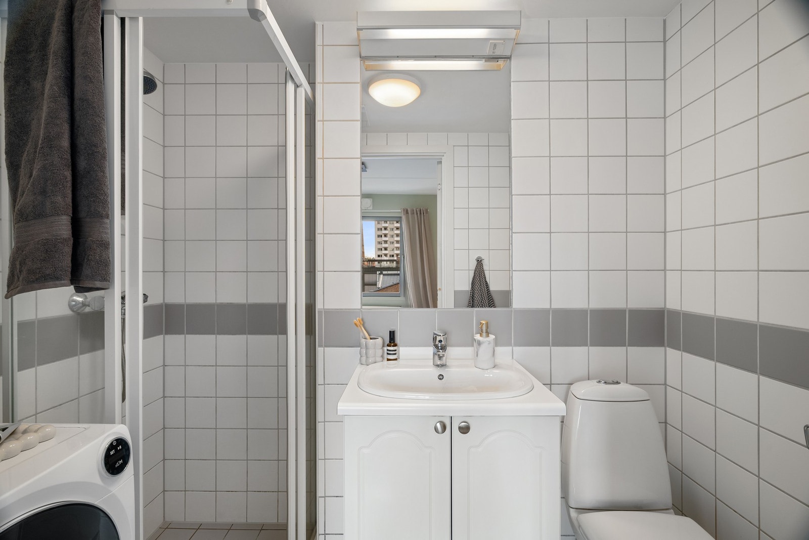 Baderommet med opplegg for vaskemaskin, toalett og dusjhjørne i herdet glass Galleribilde