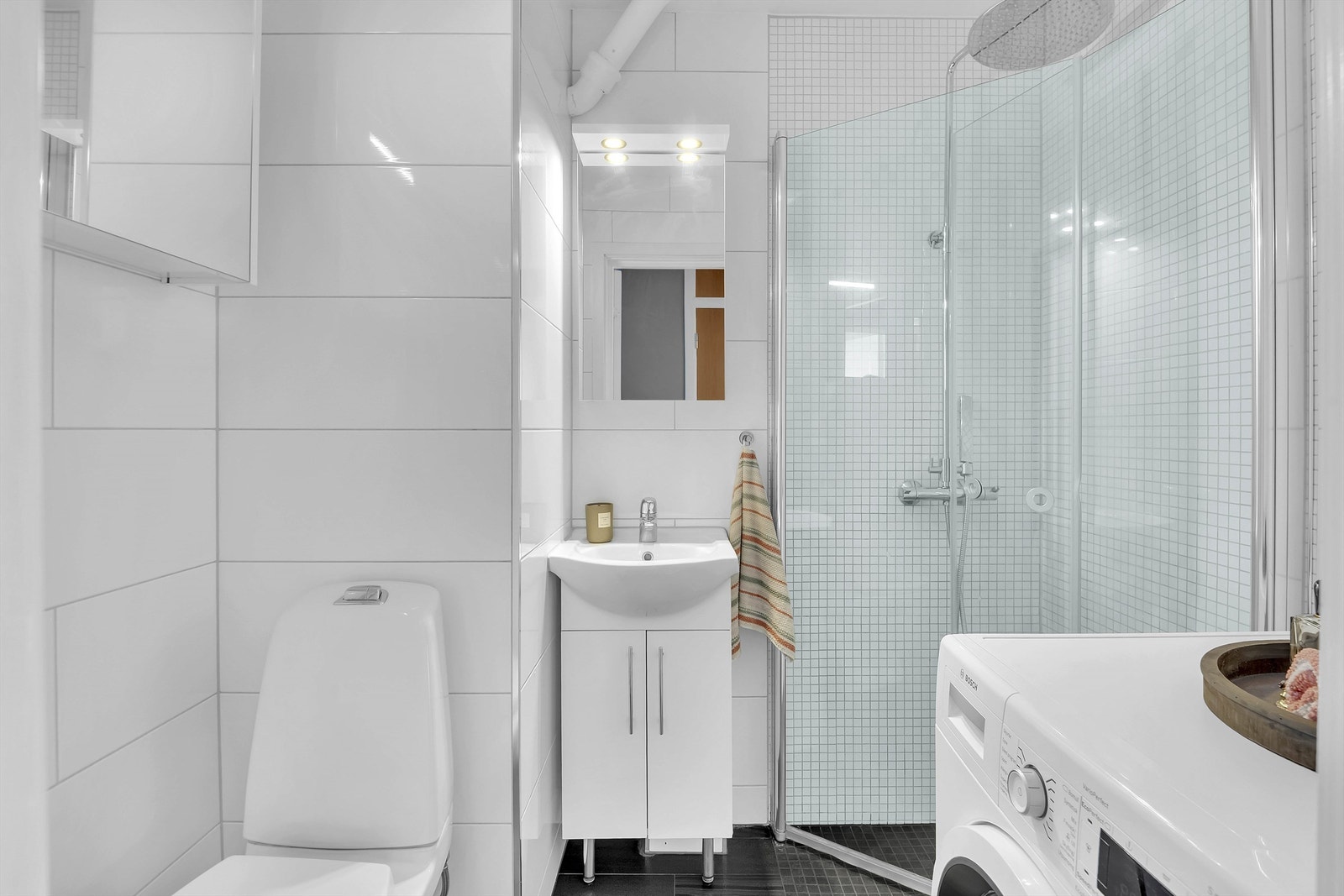 Bad fra 2015 i følge eier med flislagte vegger og malt himling. Det er dusjhjørne med glassdører og dusjgarnityr, gulvmontert toalett, servantskap med servant og ett greps blandebatteri. Galleribilde