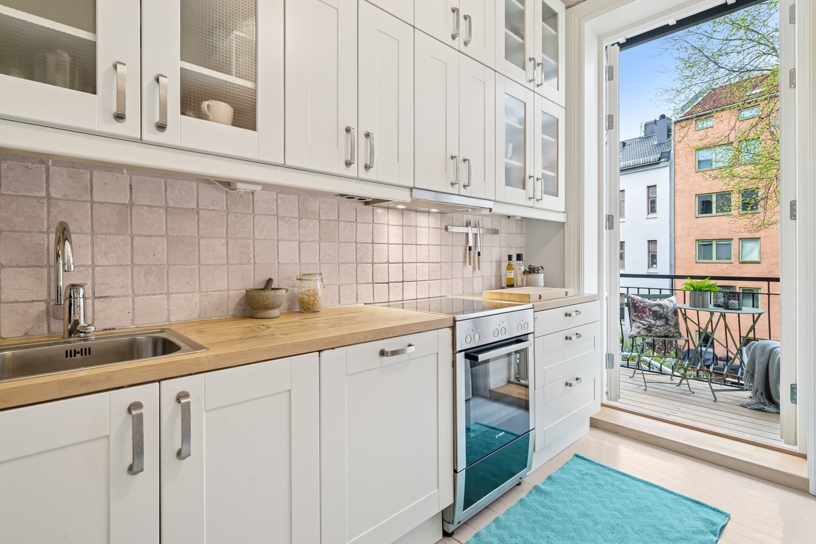 Kjøkkenet har takhøy innredning med doble overskap, profilerte hvite fronter og vitrineskap. Benkeplaten er i heltre eik, med fliser over benken for en praktisk og stilren finish. Integrert oppvaskmaskin. Galleribilde