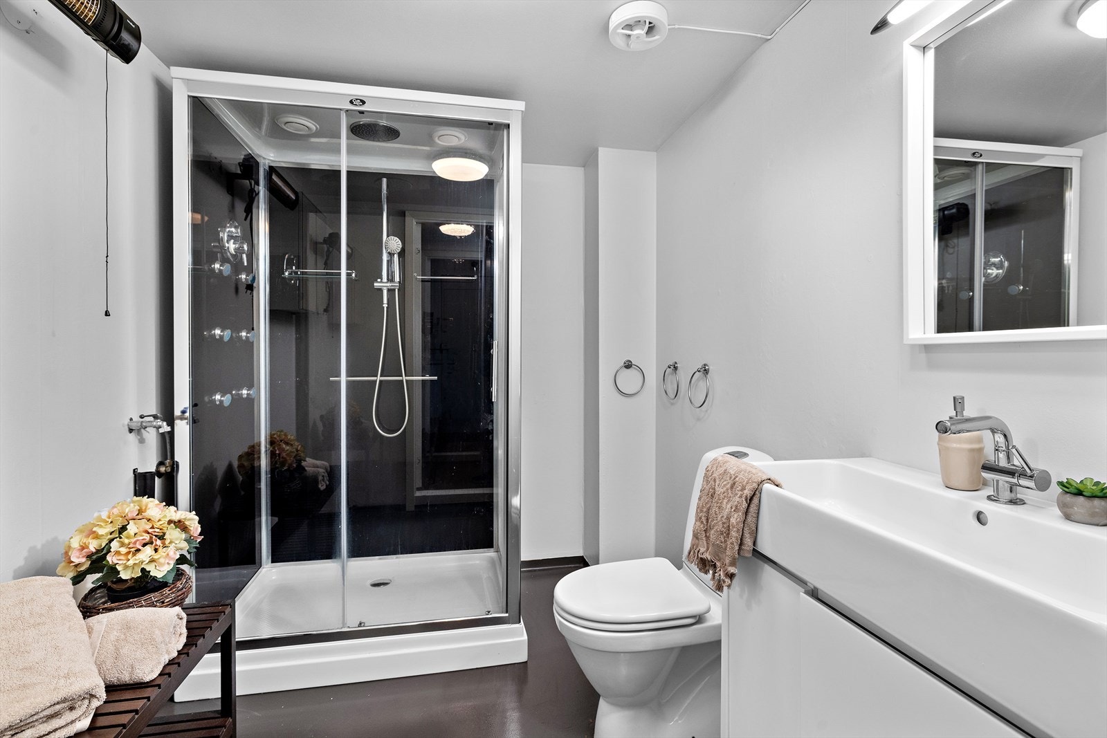 Baderom med dusjkabinett, toalett, servantinnredning og opplegg for vaskemaskin. Galleribilde