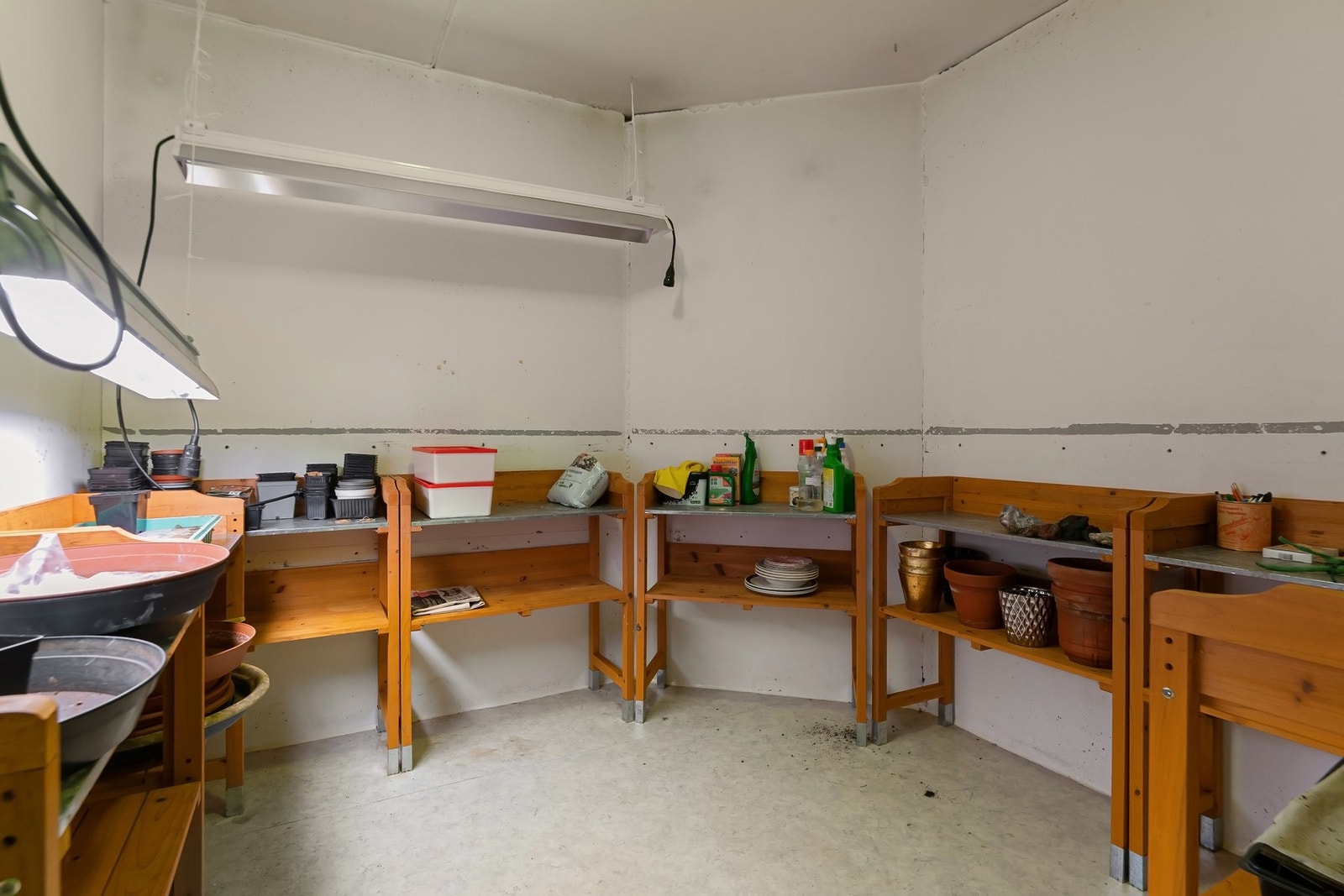 Innvendig bod med tappekran, utslagskum, benker og belysning egnet til å dyrke og drive frem planter. Galleribilde