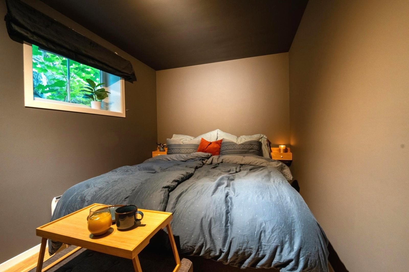 Romslig soverom med mørke farger som skaper en god og lun soveromsfølelse Galleribilde