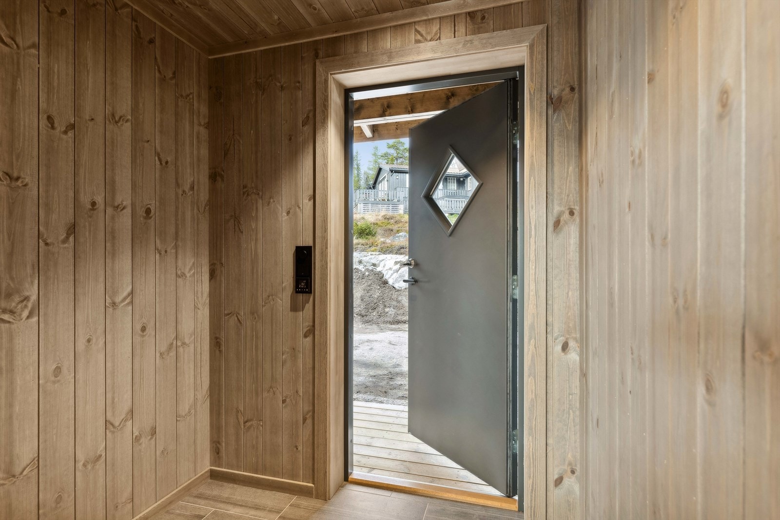 Stig på! Vindfanget gir et fint førsteinntrykk. Her er god plass til yttertøy og sko. Gulvet er flislagt og har varmekabler. Galleribilde