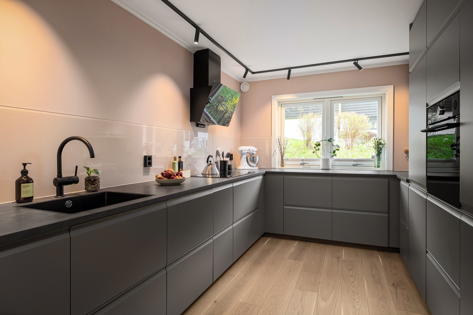 Kjøkkeninnredning fra Ikea med mørke, slette fronter, benkeplate av laminat og nedfelt oppvaskkum med ett-greps kjøkkenarmatur Galleribilde