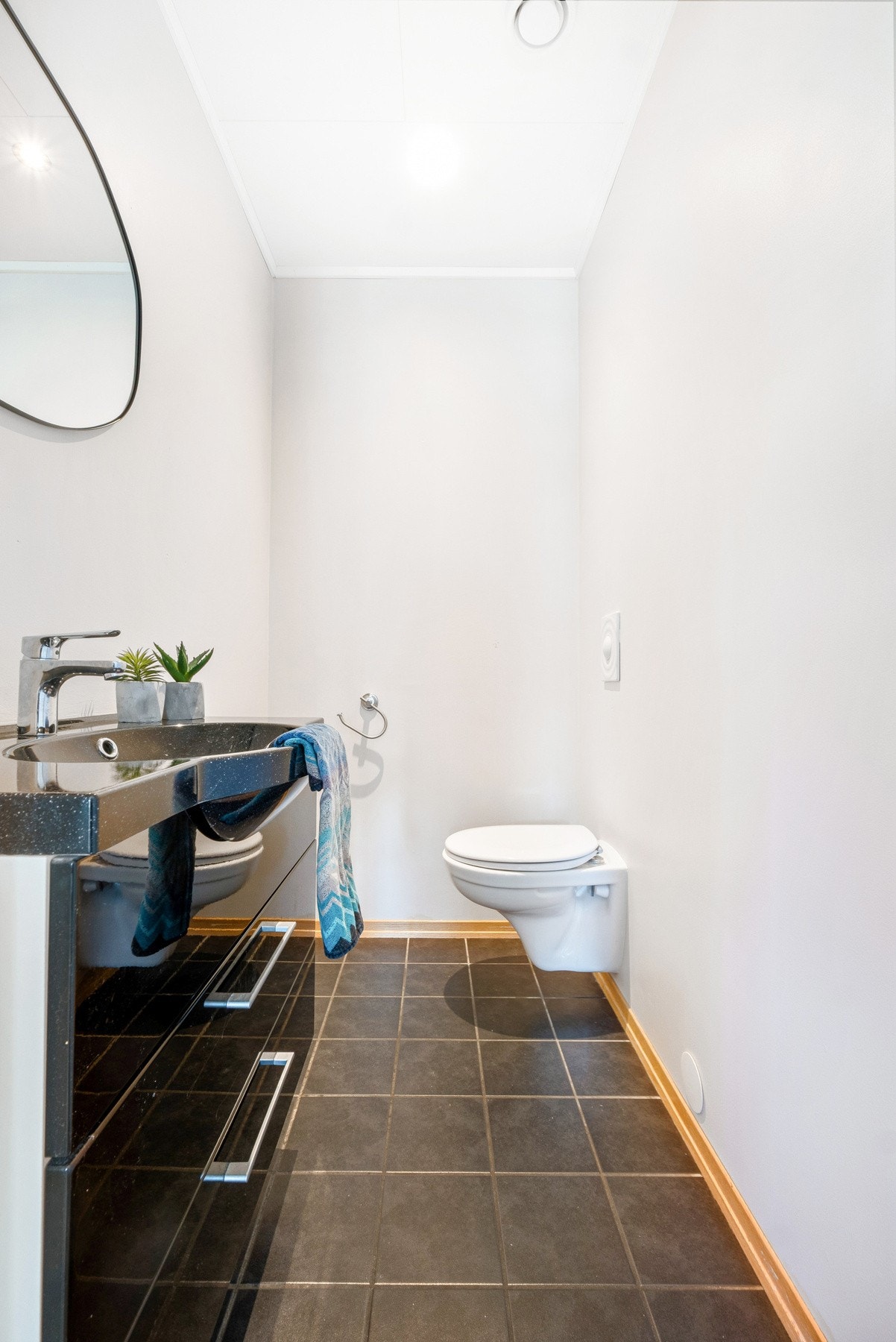 Gjestetoalett i 1. etasje med moderne fliser, vegghengt toalett og enkel servant. Galleribilde