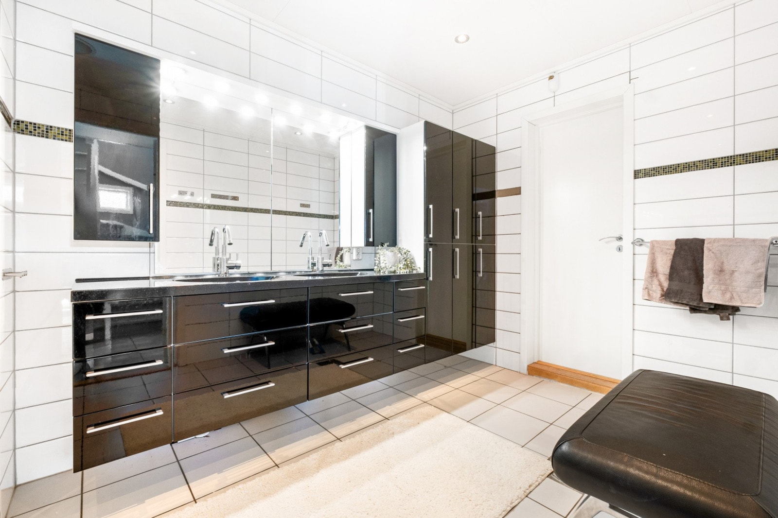 Helfliset med hvite fliser og rikelig oppbevaringsplass i mørke skap. Galleribilde