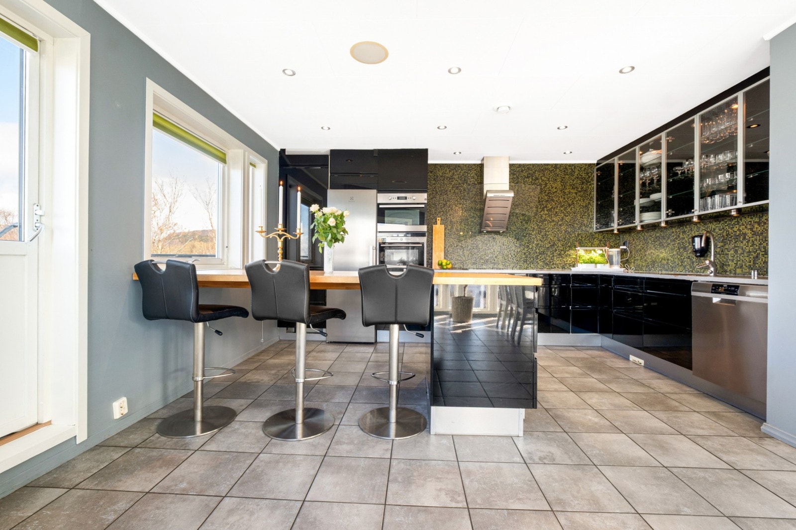 Innredningen har sorte, høyglansede fronter og en praktisk kjøkkenøy med barstoler, ideell for uformelle måltider. Galleribilde