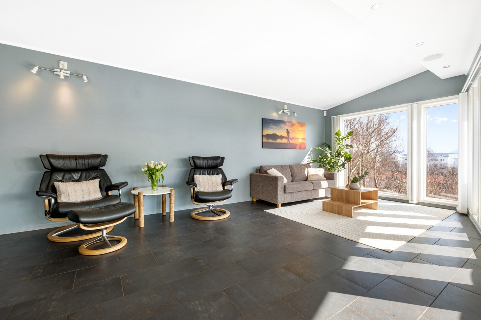 Rommet er møblert med komfortable, svarte skinnstoler og en sofa, perfekt for avslapning. Galleribilde