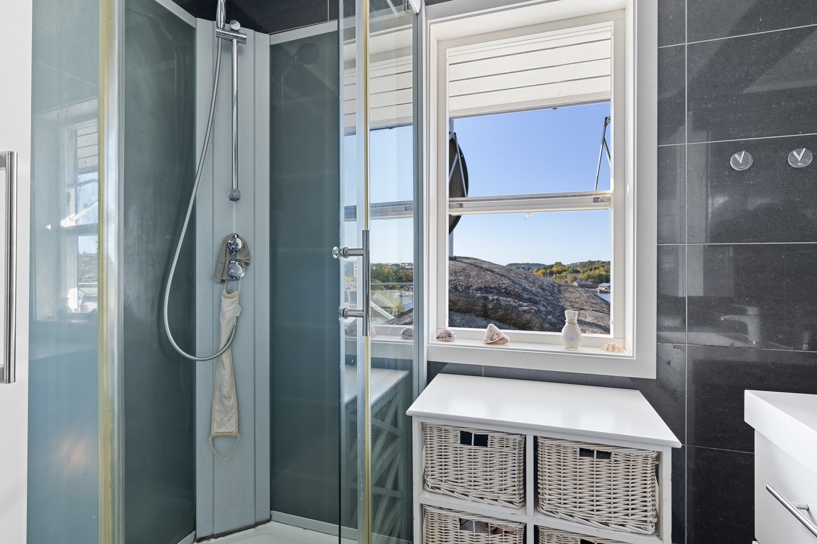 Badet benyttes med dusjkabinett som begrenser vannpåkjenning på overflatene. Gulv og vegger er flislagt. Galleribilde