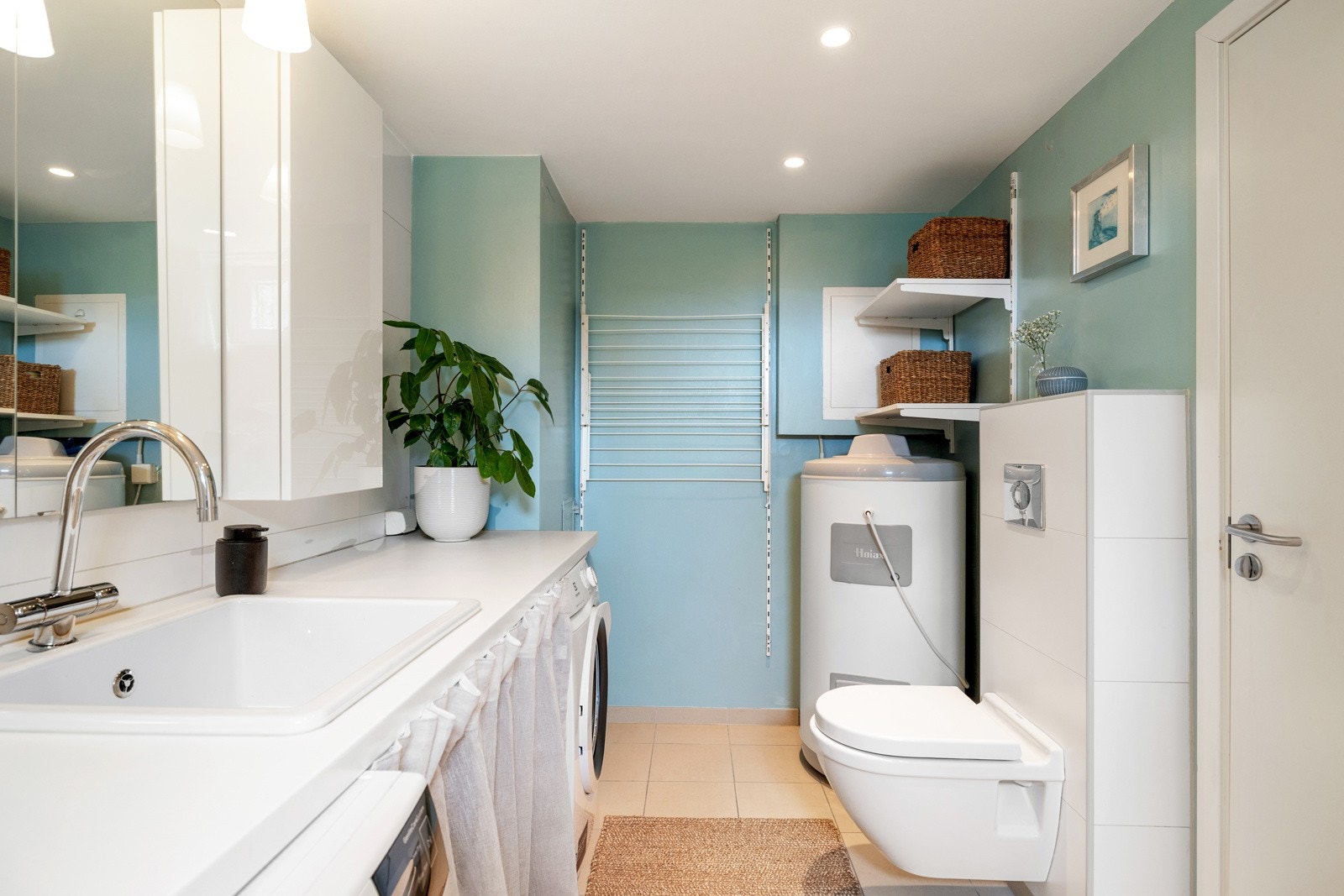 Badet i underetasjen er innredet med enkel servant, opplegg for vaskemaskin, plass til tørketrommel og badekar. Galleribilde