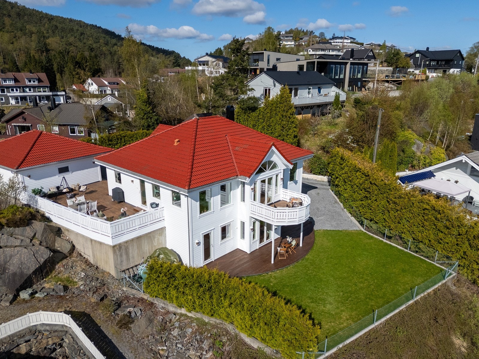 Eiendommen ligger på en pent opparbeidet tomt med gruset innkjørsel og biloppstillingsplasser, gressplen og terrassedekker som gir gode og solrike uteplasser. Galleribilde