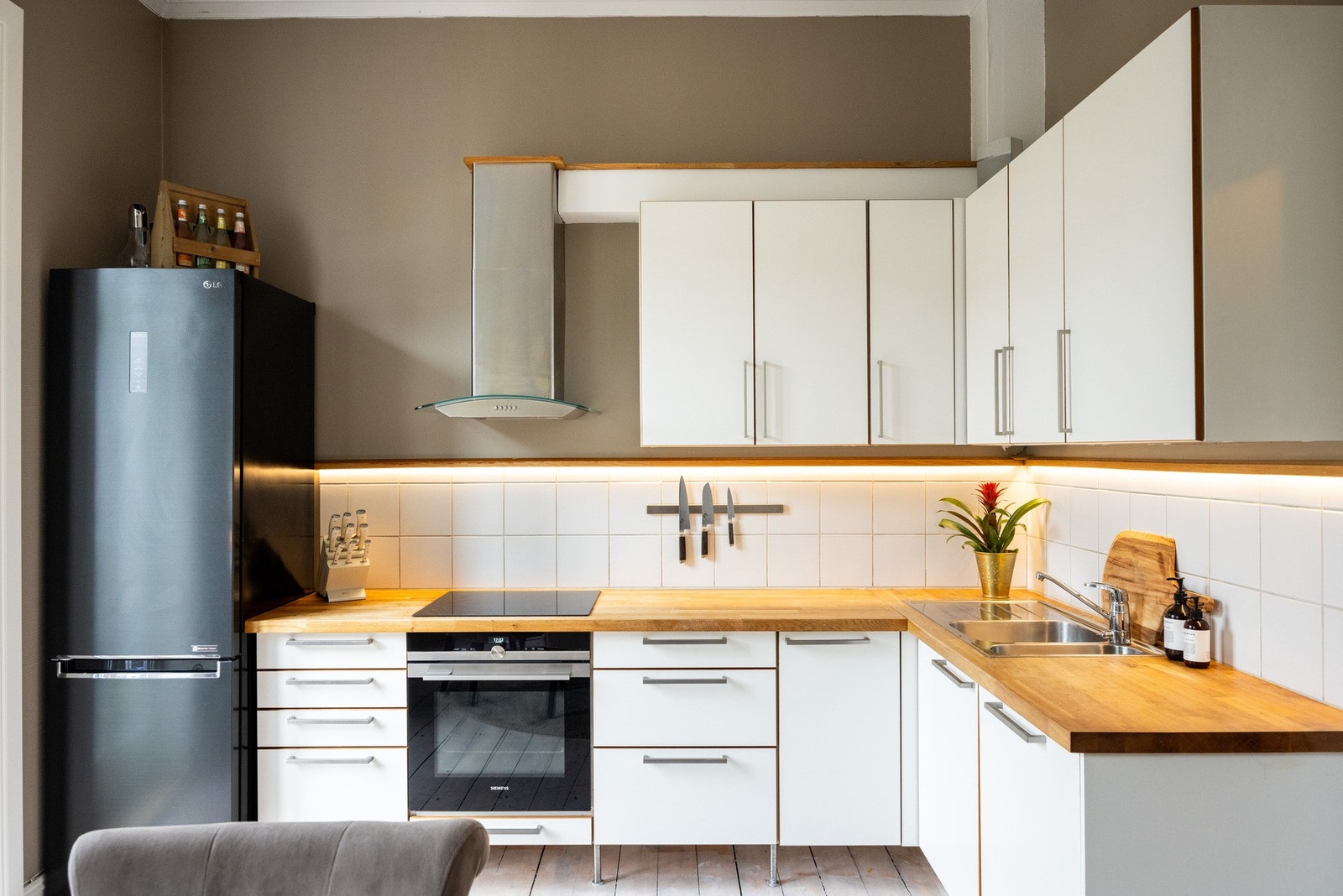 Integrerte hvitevarer som induksjonsplatetopp, stekeovn og oppvaskmaskin, samt frittstående kjøleskap. Galleribilde