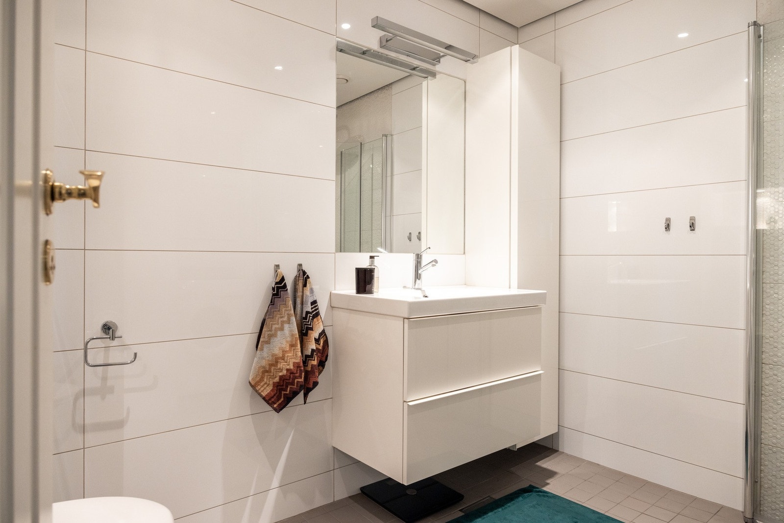 Badet er innredet med servantskap, vegghengt toalett og dusjhjørne med innfellbare dusjdører. Galleribilde