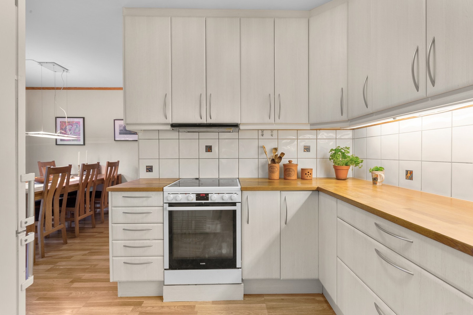 Kjøkkeninnredningen består av glatte fronter, benkeplate i flott heltre eik, samt nedfelt kum i rustfritt stål.
Fliser på vegg over benk. Galleribilde