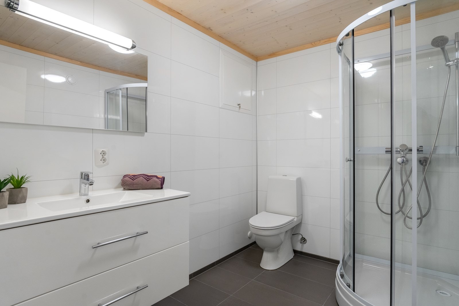 Pent bad med mørke fliser på gulv og baderomsplater på vegg. Galleribilde