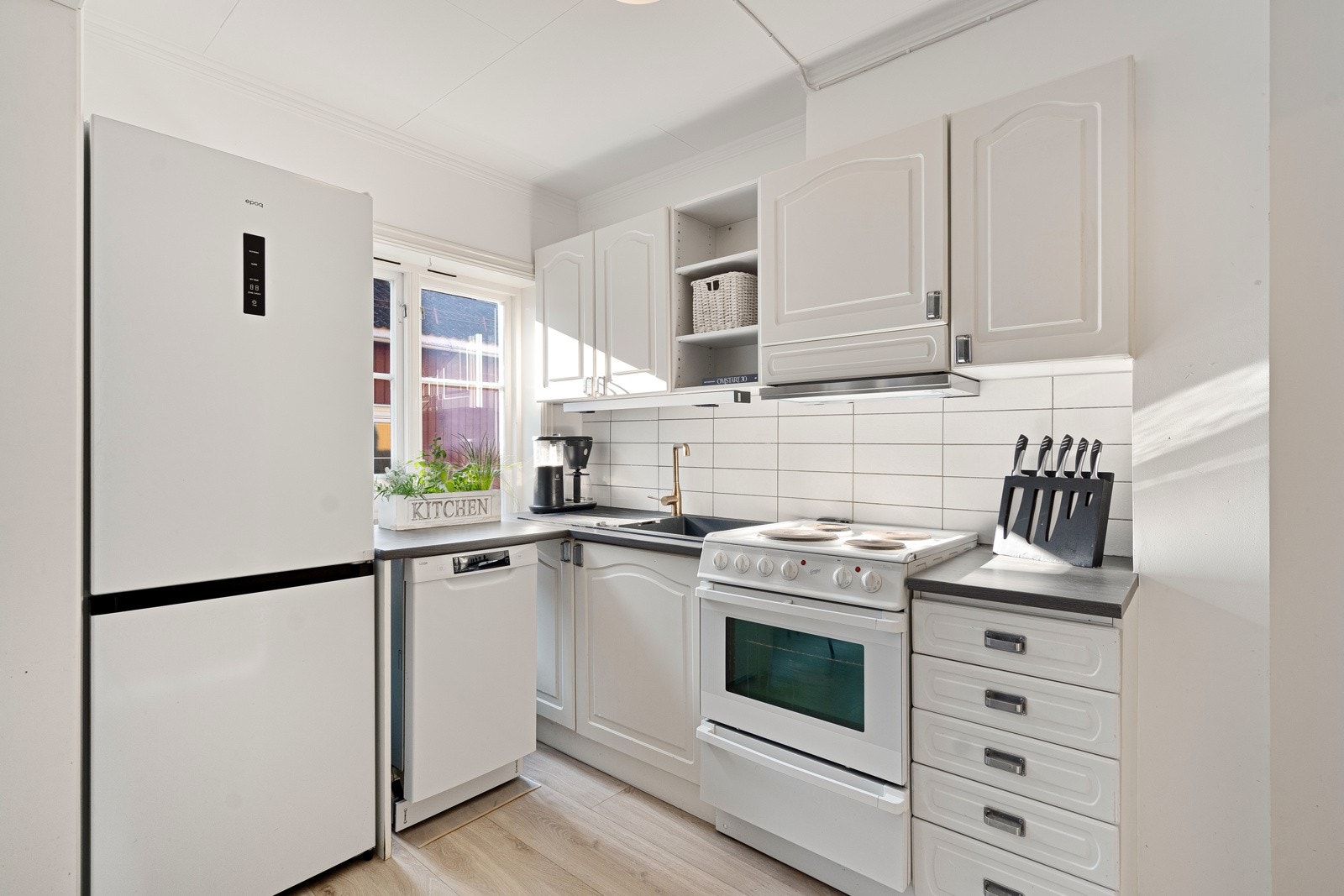 Hvite fliser er montert over benken, og over kokesonen har kjøkkenet en ventilator. Opplegg for oppvaskmaskin er etablert. Galleribilde