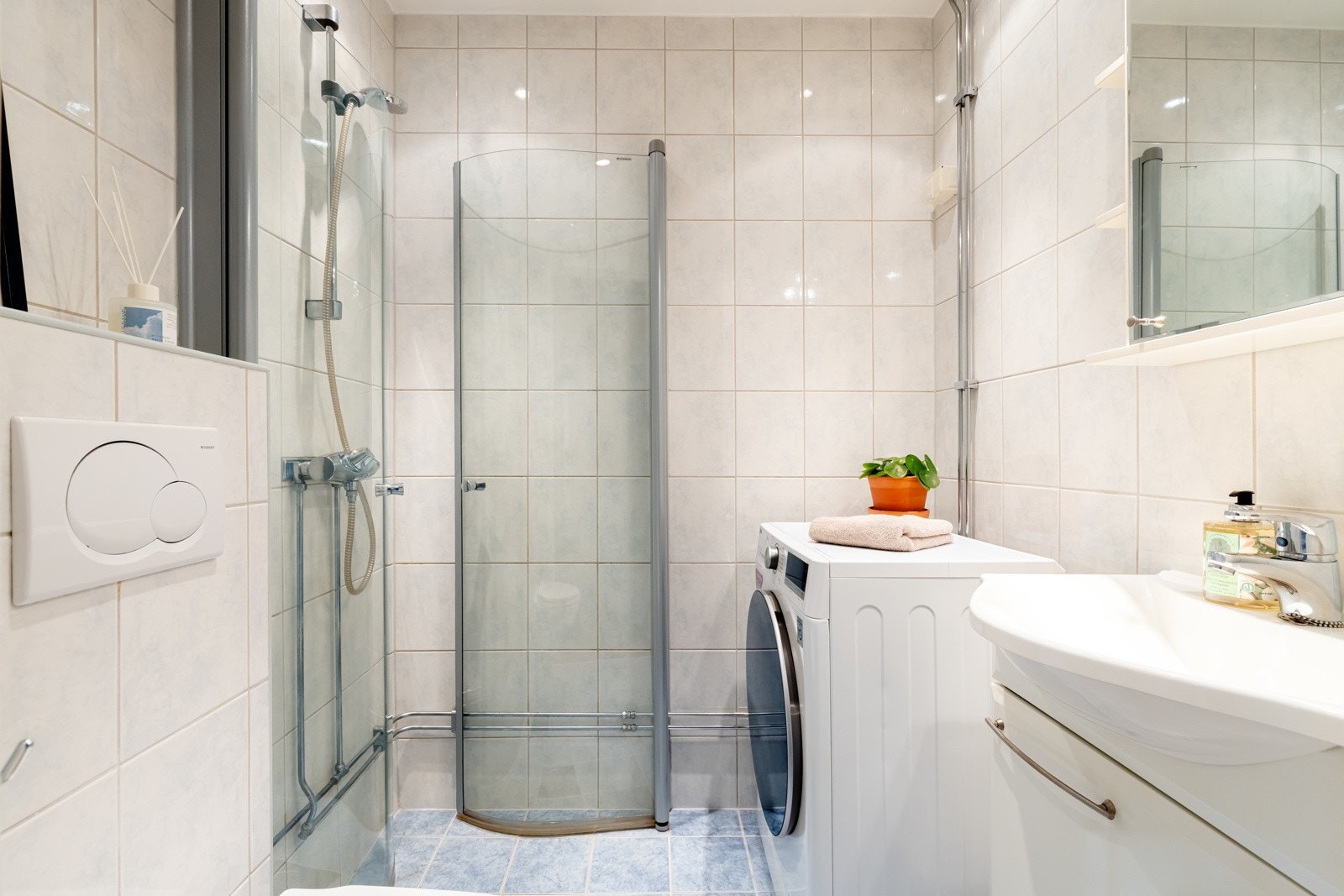 Badet består av vegghengt servantinnredning med dører, ovenpåliggendde servant med ett-greps armatur, dusjhjørne med glassdører og vegghengt toalett. Galleribilde