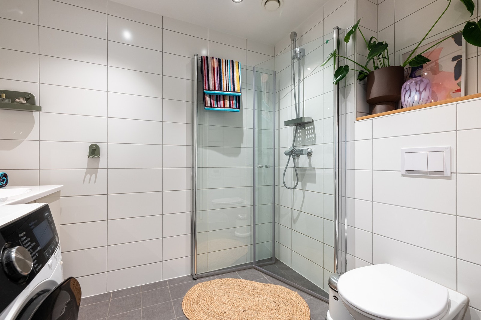 Videre er det vegghengt toalett og dusjhjørne med svingbare glassdører som frigjør plass på gulvet. Praktisk nisje over toalettet byr på plass til dekor og planter. Galleribilde