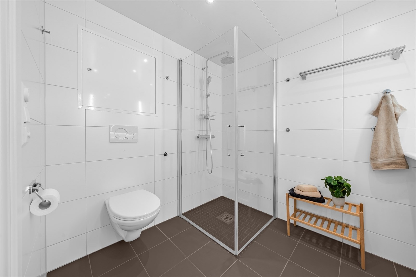 Innredningen består av vegghengt klosett, servant på møbelinnredning og dusjhjørne med glassvegger. Galleribilde