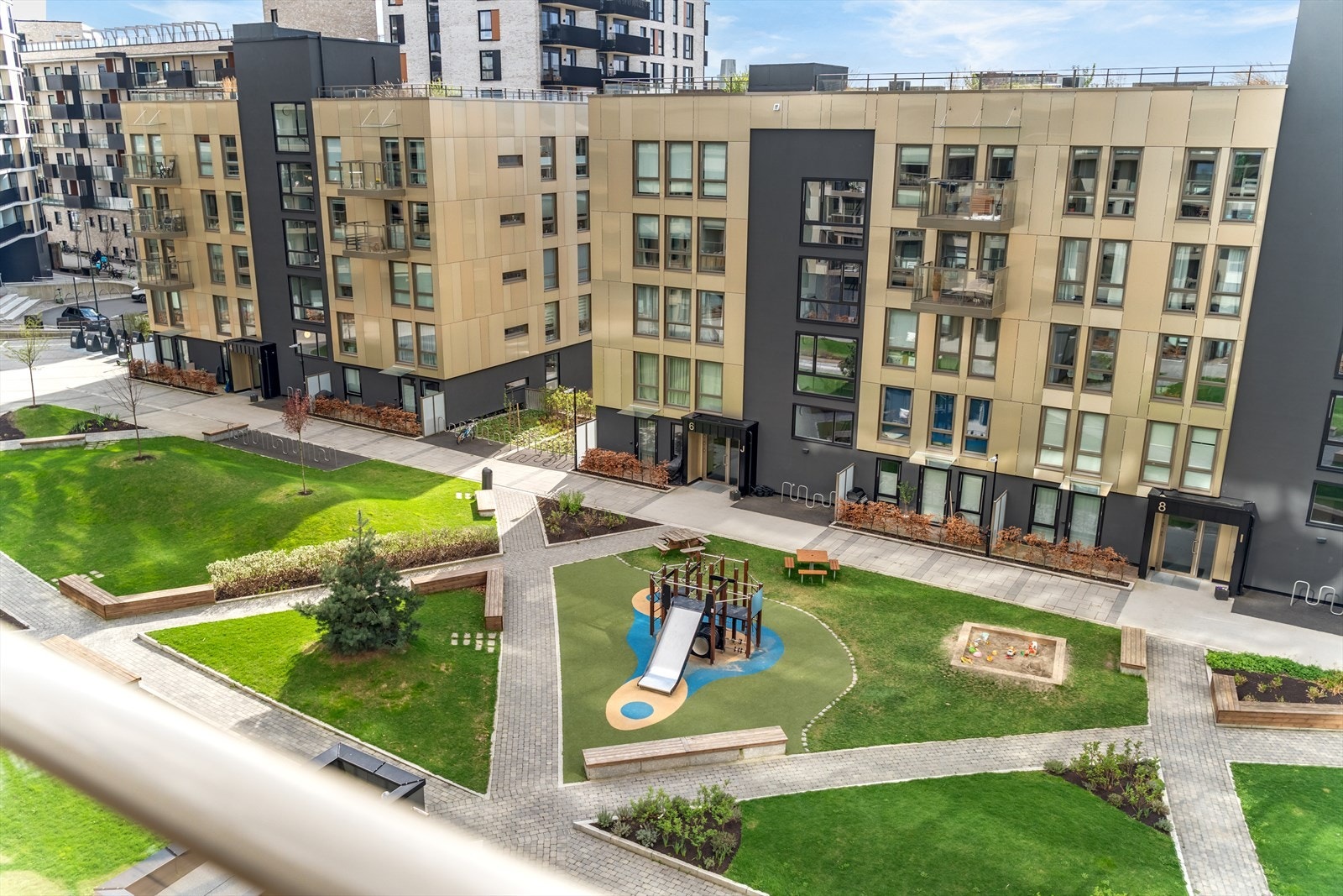 Balkongen vender ut mot en rolig og velstelt gårdsplass. Denne er flott opparbeidet med lekne og trygge lekeapparater for de minste, samt hyggelige sittegrupper som skaper en innbydende atmosfære for både avslapning og samvær. Galleribilde