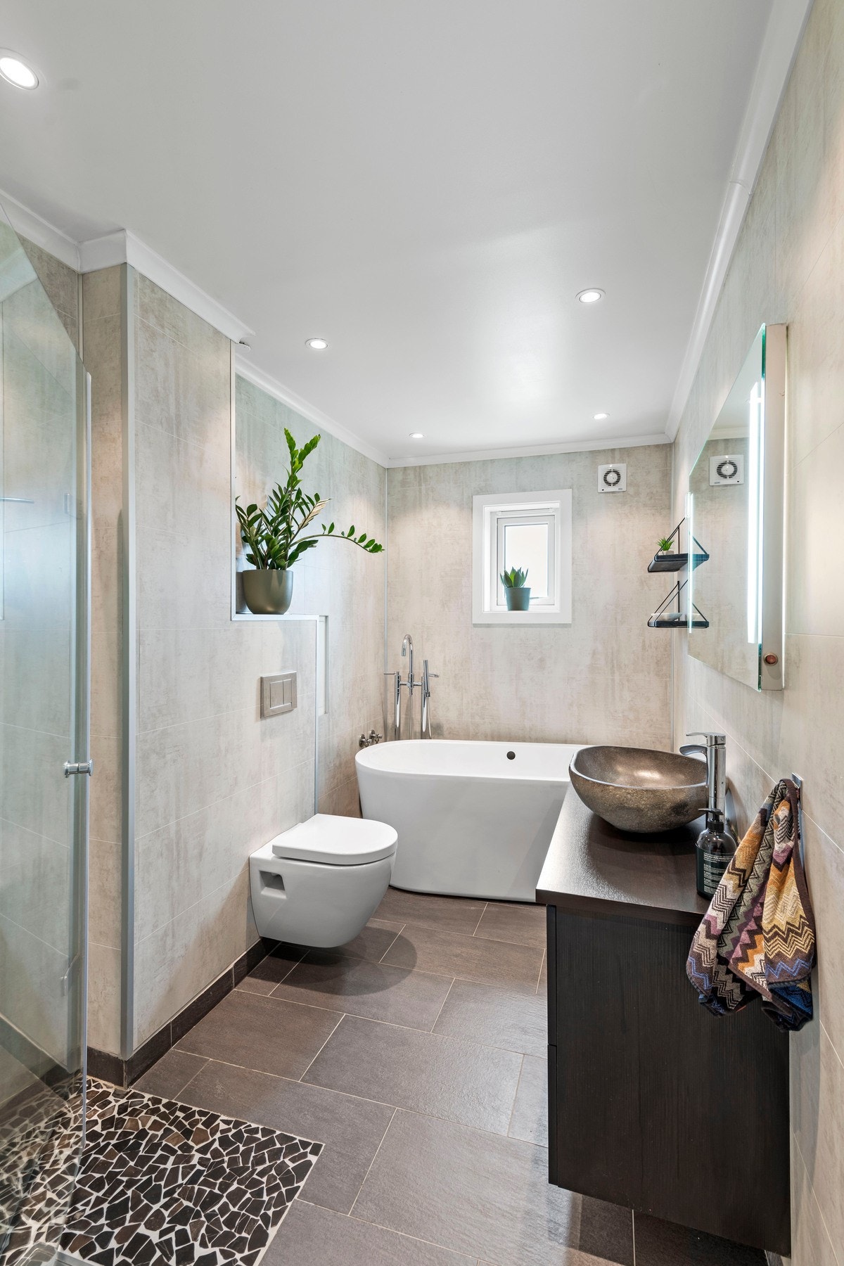 Leiligheten har et lekkert bad som ble pusset opp i 2014/15. Badet har mørke fliser på gulvet og fine betonglignende baderomsplater på veggene. Galleribilde