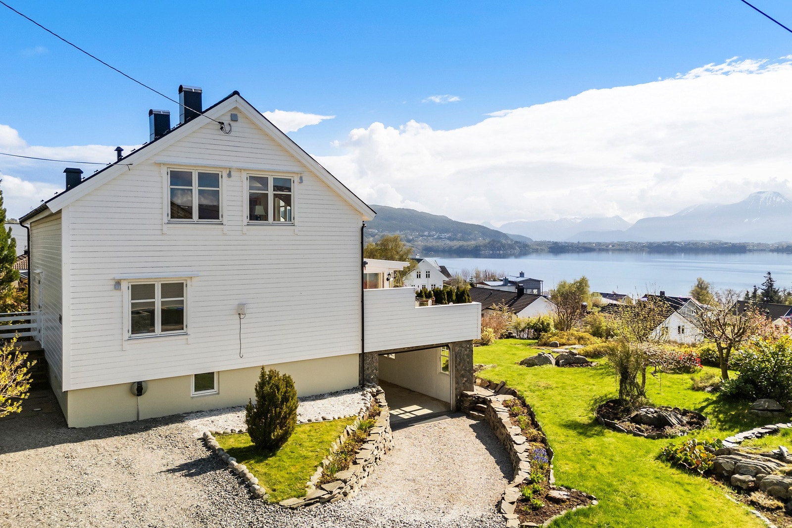 På vestveggen under stuevindu er det montert elbil- lader, denne fra 2022. Legg også merke til den vakre hagen. Galleribilde