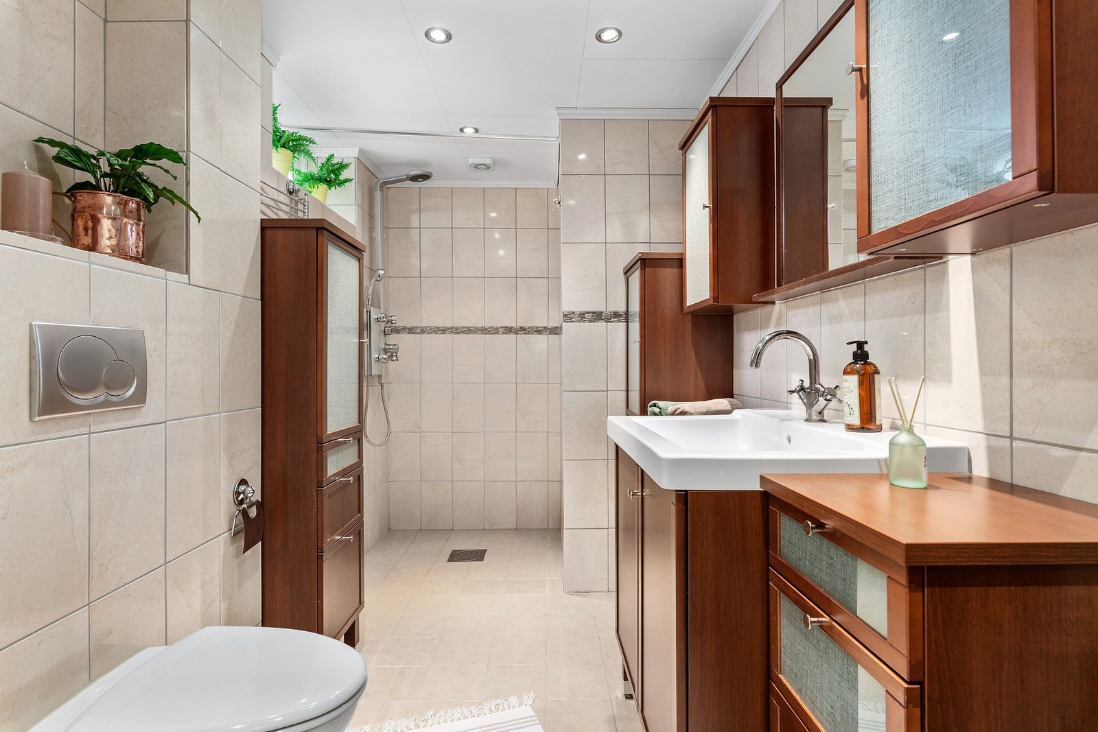 Badet i underetasjen er helfliset, har nedsenket gulv i dusjsone, vegghengt toalett og romslig porselenservant. Galleribilde