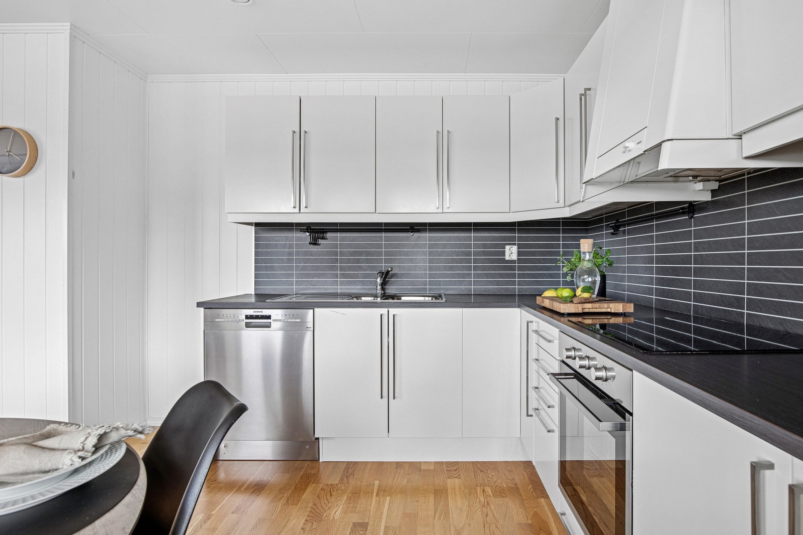 Her er det plater med flistrykk mellom benk og overskap som gir et rent design, samt belysning og stikkontakter under overskap som gjør kjøkkenet funksjonelt. Galleribilde