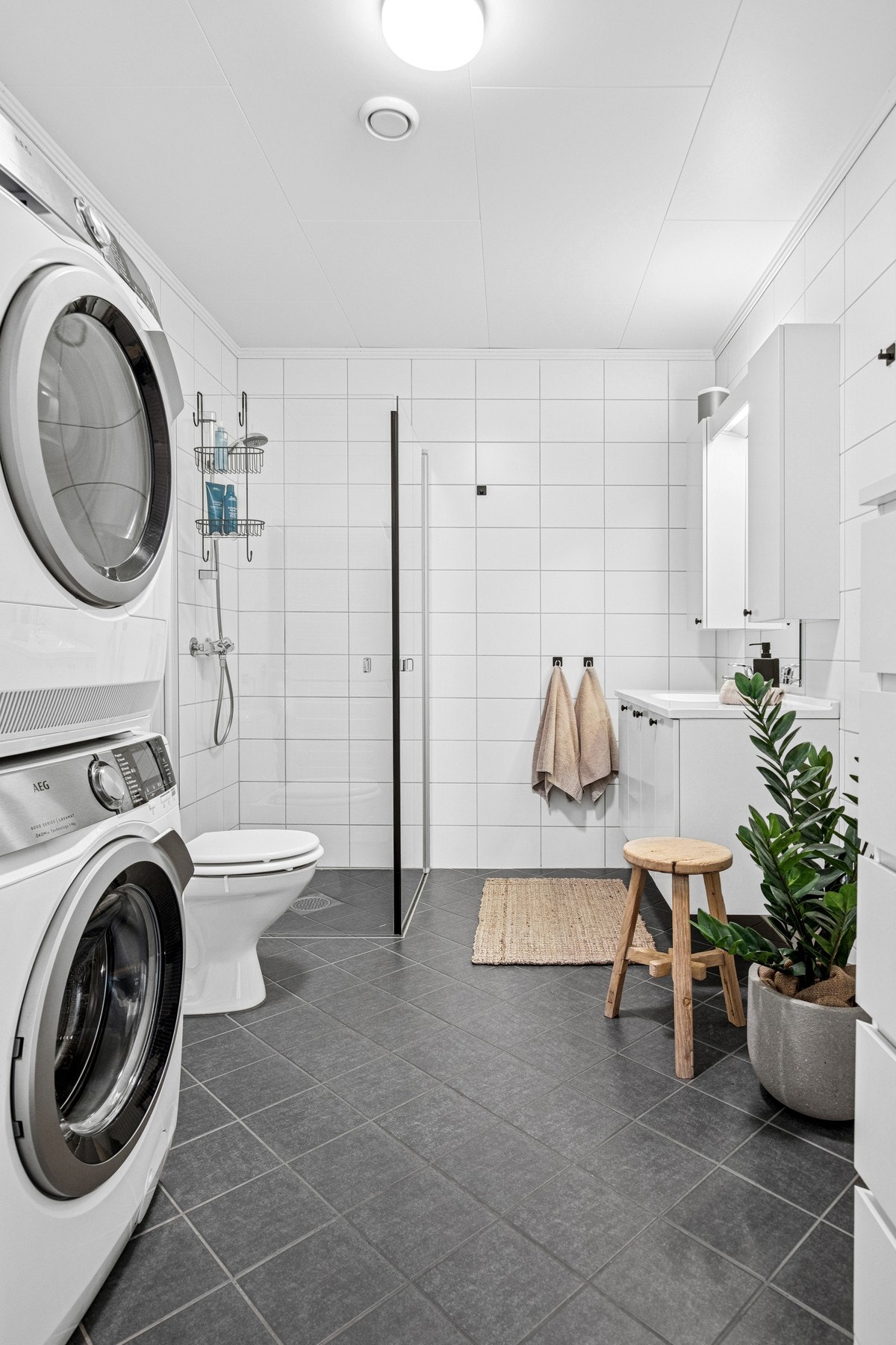 Romslig flislagt bad med praktisk innredning og gulvvarme. Galleribilde