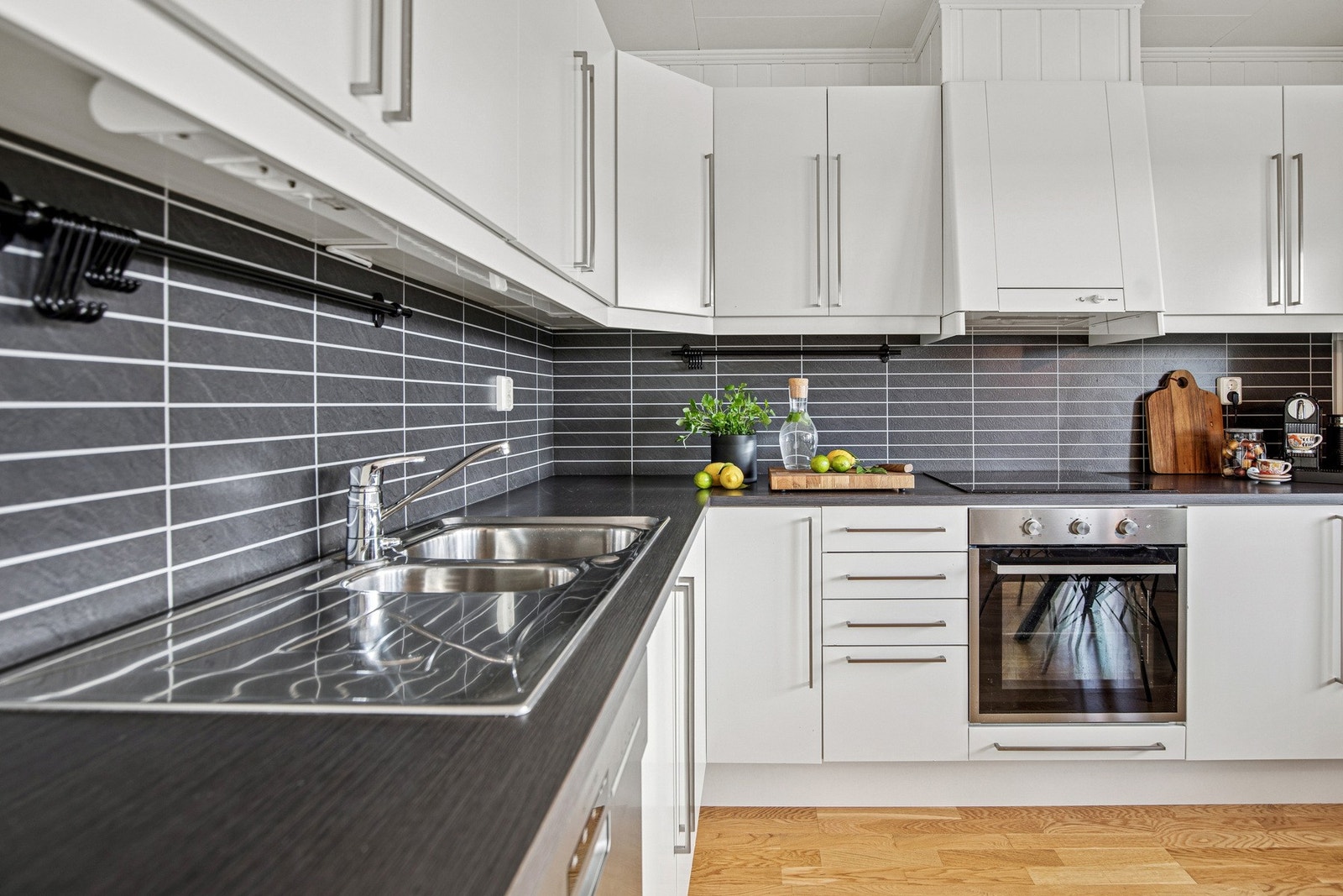 Stilrent kjøkken med god benkeplass og integrert komfyr. Mørk laminert benkeplate og moderne flisplater gir en flott kontrast mot de lyse frontene. Galleribilde